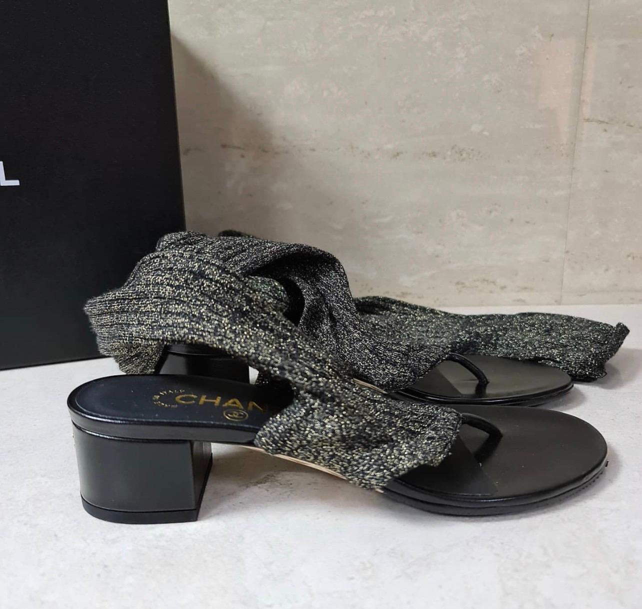 Details:

- Elasticized ribbed black/gold metallic textile over-the-knee socks.

- Black leather thong sandal.

- Self covered heel.

- Gold-tone metal CC logo at back of heel.

- Leather insole and sole.

Sz 38

Condition is excellent.

No original