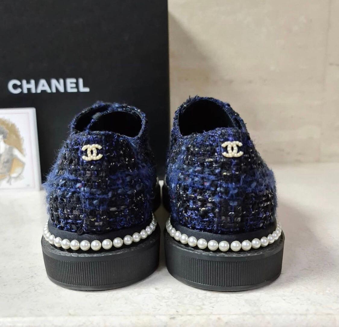 Chanel 17P Black Navy Tweed Pearl CC Logo Lace Up Flat Trainer

Lace up tie front

Chanel CC back pearl logo

Black grosgrain cap toe

Black navy blue tweed fabric material

Pearl trim around perimeter

Pearl detail lace up rings

Sz 38,5

Condition