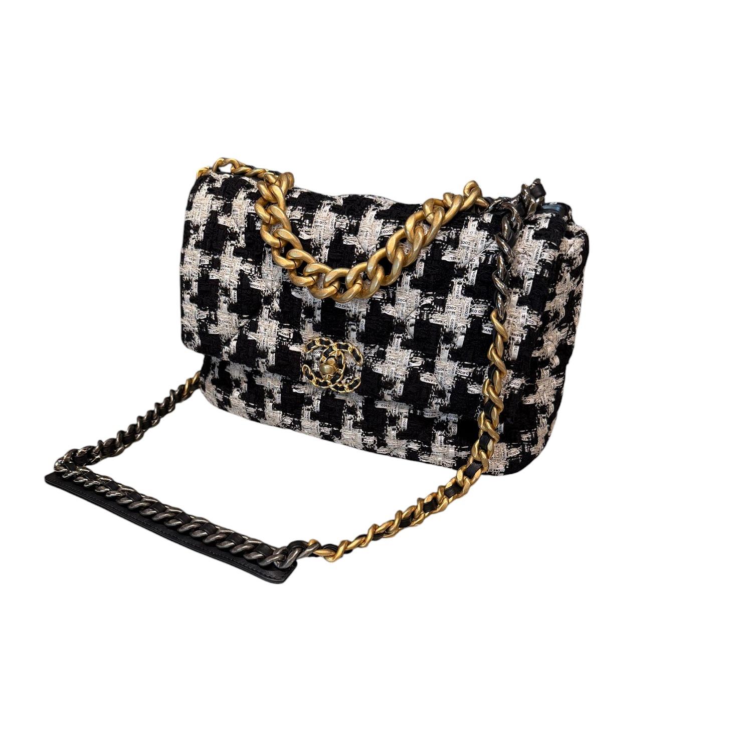 This chic shoulder bag is crafted of black and white tweed with a white Chanel ribbon weaved in. The refined bag features an aged gold chain detail CC turn-lock on the flap, a magnetic snap pocket at the rear, and a leather threaded gradient gold to