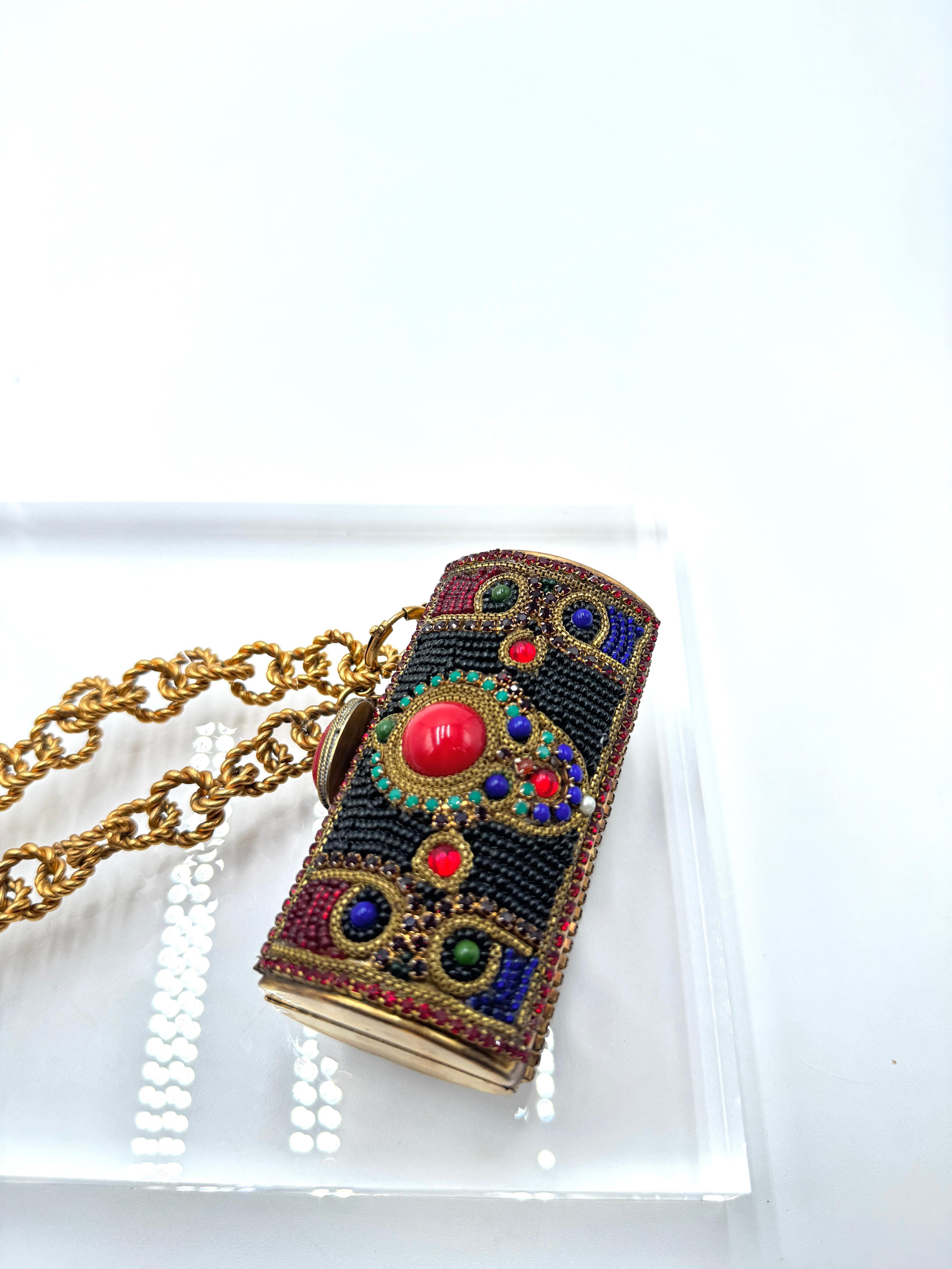 Un pezzo d'archivio eccezionalmente raro di Chanel, che si stima risalga al 1988. Questa pochette cilindrica presenta intricate perline applicate a mano, vibranti cabochon e un audace medaglione centrale. È dotato di una catena dorata di 70 cm ed è