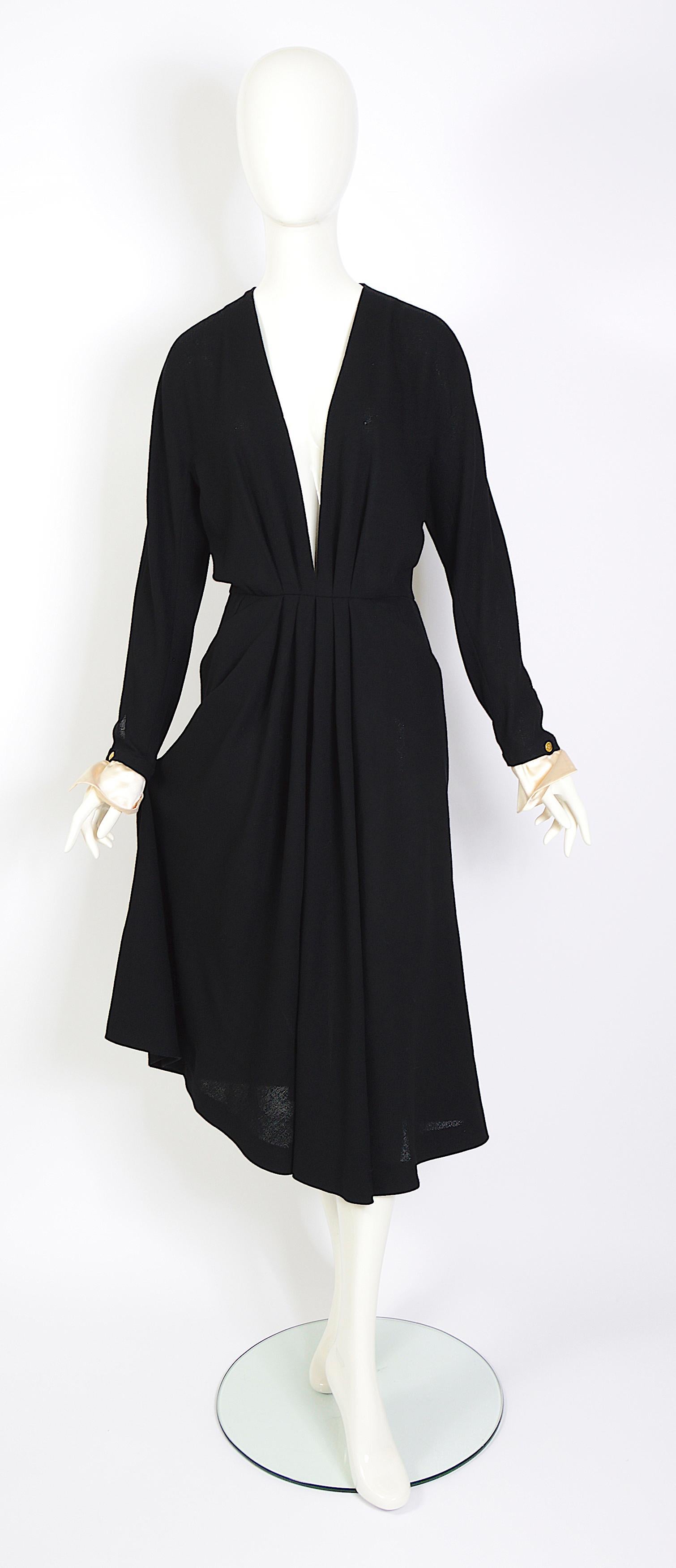 Chanel Boutique vintage 80s black deep v-neck pleated crepe dress with detachable white satin cuffs. Designed by Karl Lagerfeld, you feel the old-school Chanel and Ines de la Fressanges decade. 
The elegance and beauty of this dress are truly