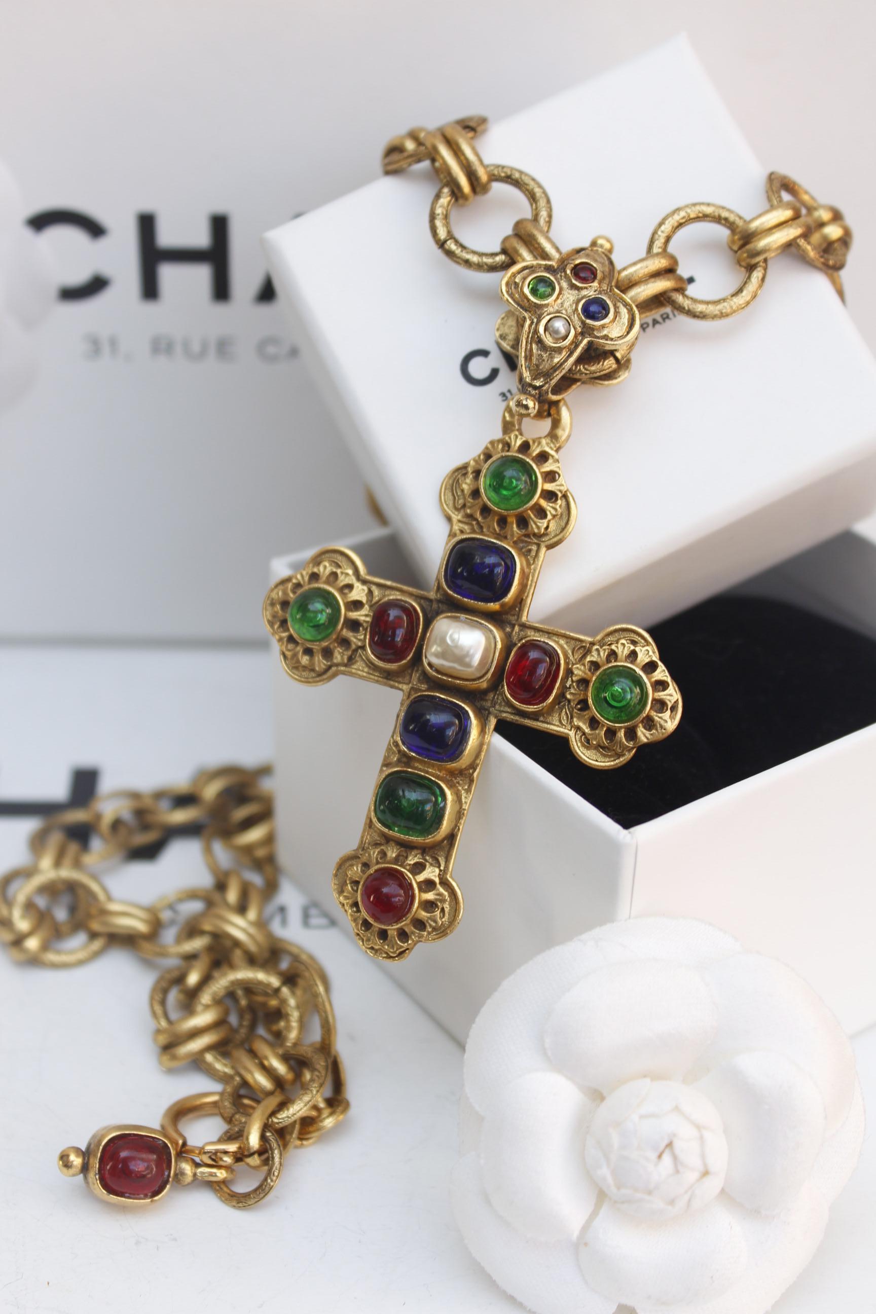 CHANEL (Made in France) 

Beautiful long necklace composed of a large stylized gilted metal chain and adorned by a jewel cross pendant, decorated with pearly and glass paste cabochons in blue, red and green colors.

Signed on a plate at the back of