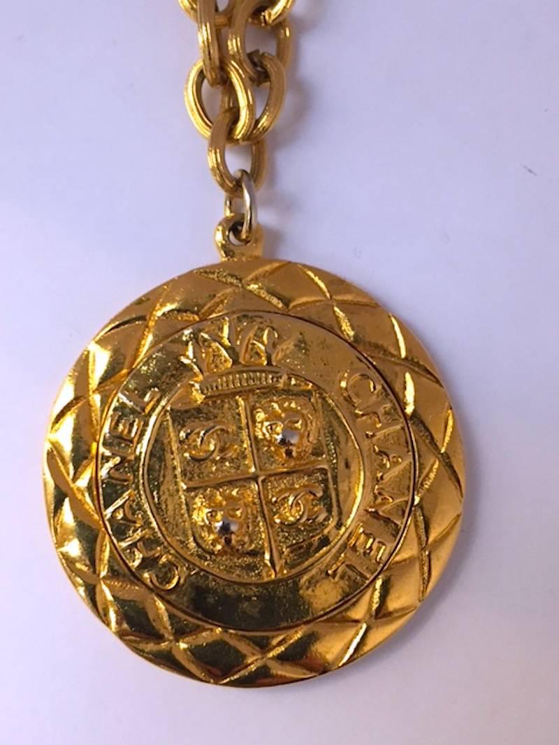 Late 1970s to early 1980s Chanel reversible gold pendant necklace. One side of the 1.75 inch (4.5 cm) round coin has a crest with Chanel written twice, two double CC logo and two lion faces in the crest. On the reverse is a diamond with crown crest