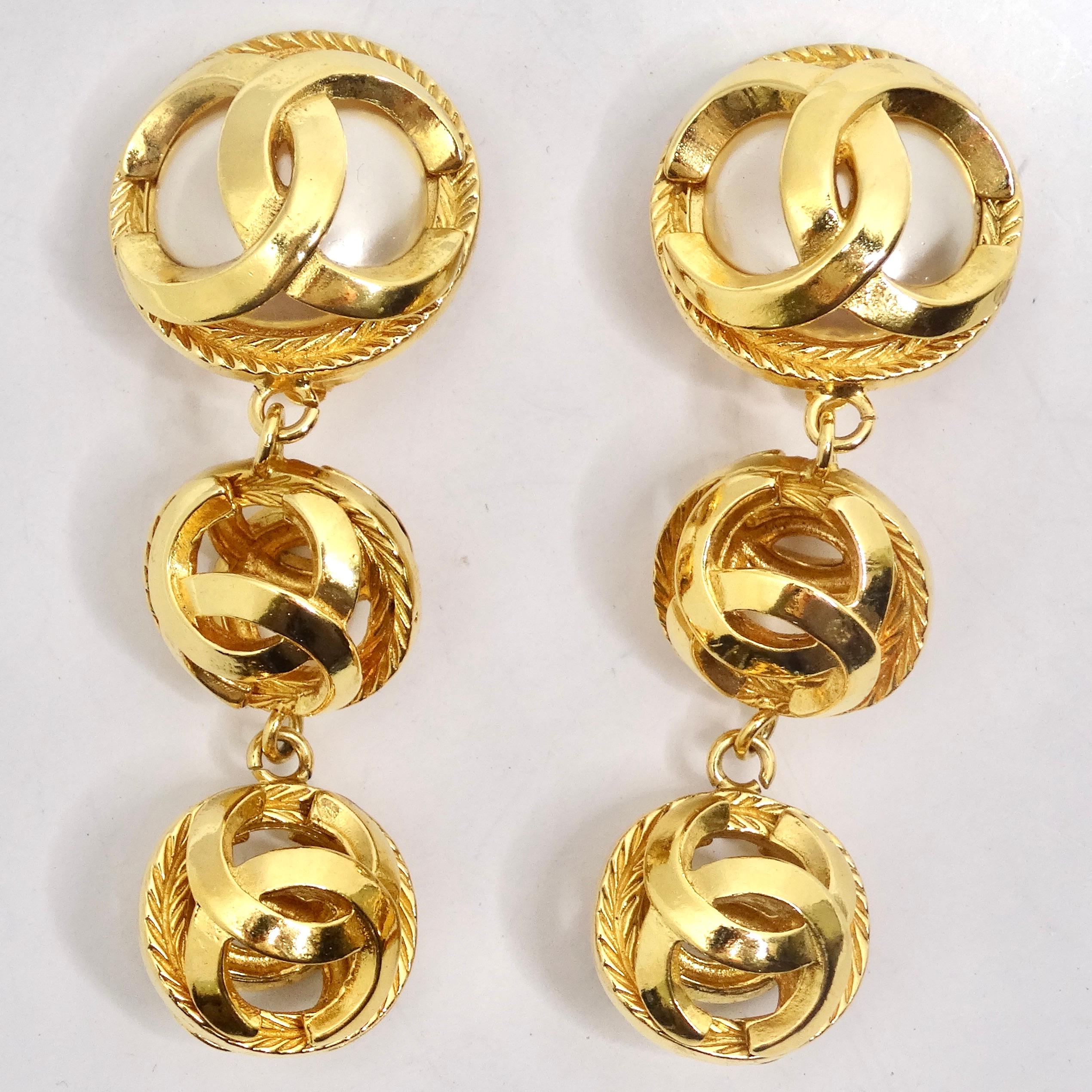 Wir präsentieren ein Paar exquisite Ohrringe aus den 1980er Jahren, die Chanel Gold Tone Pearl Drop Earrings. Diese Ohrringe zeigen die perfekte Kombination der ikonischen Chanel-Design-Elemente und sind ein Muss für alle, die klassische Raffinesse