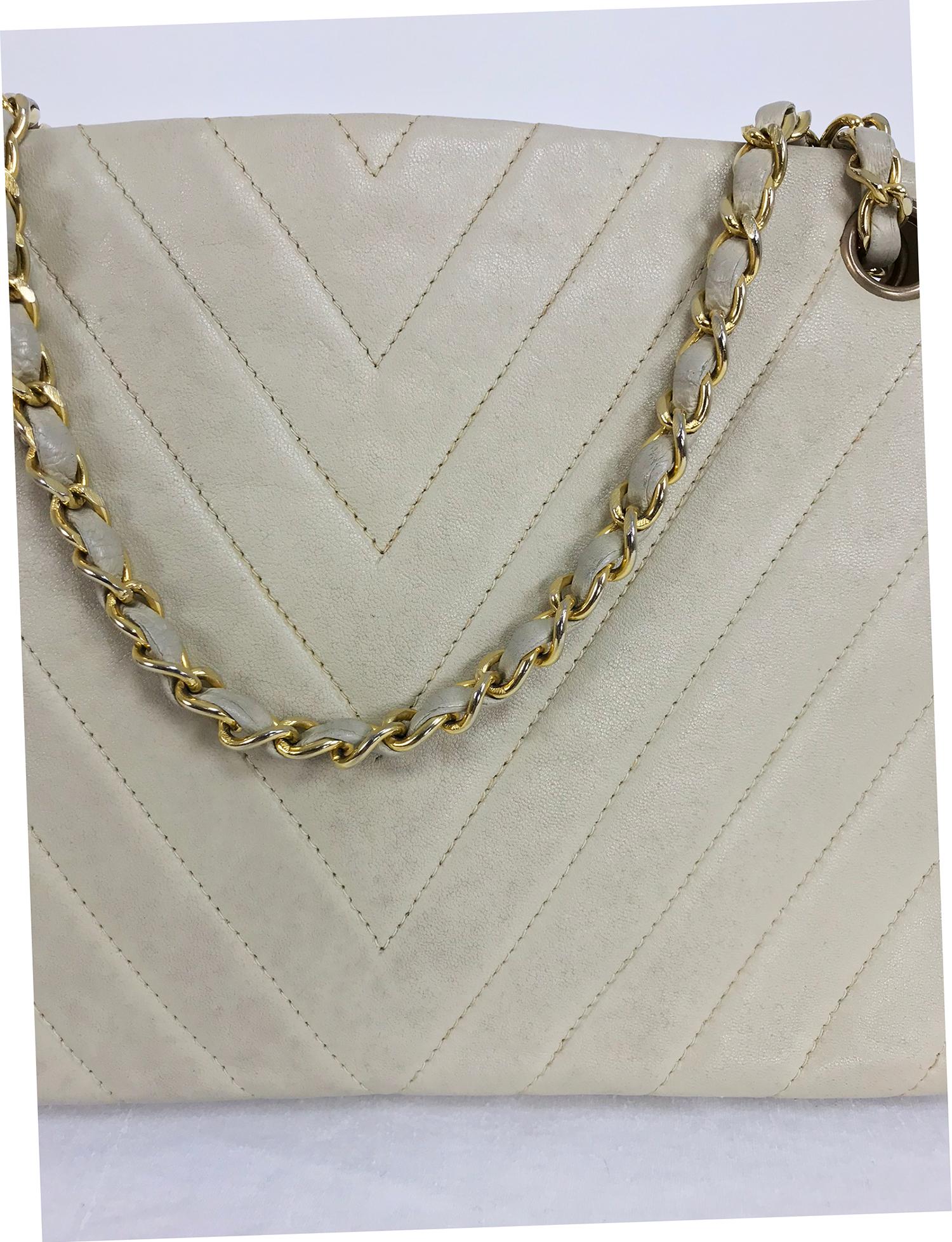 Chanel 1980s ivory chevron quilted, kiss lock, chain handle bag. Unusual Chanel bag has a center compartment that closes with a kiss lock clasp, inside you will find cream leather lining with silk interiors. There is a flap compartment with a slip