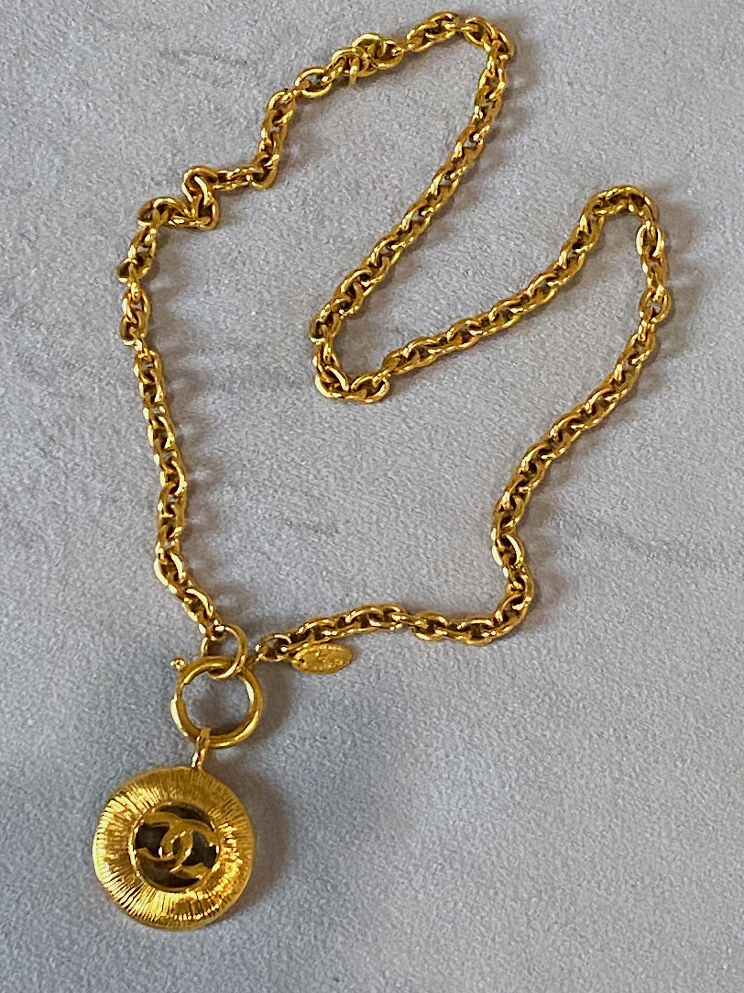 A classic design by Chanel from the 1980s is the gold tone domed pendant necklace. The chain is an oval cable link a quarter of an inch wide and 23 inches long including the large jump ring. The round pendant is 1.19 inches in diameter and 1.5 