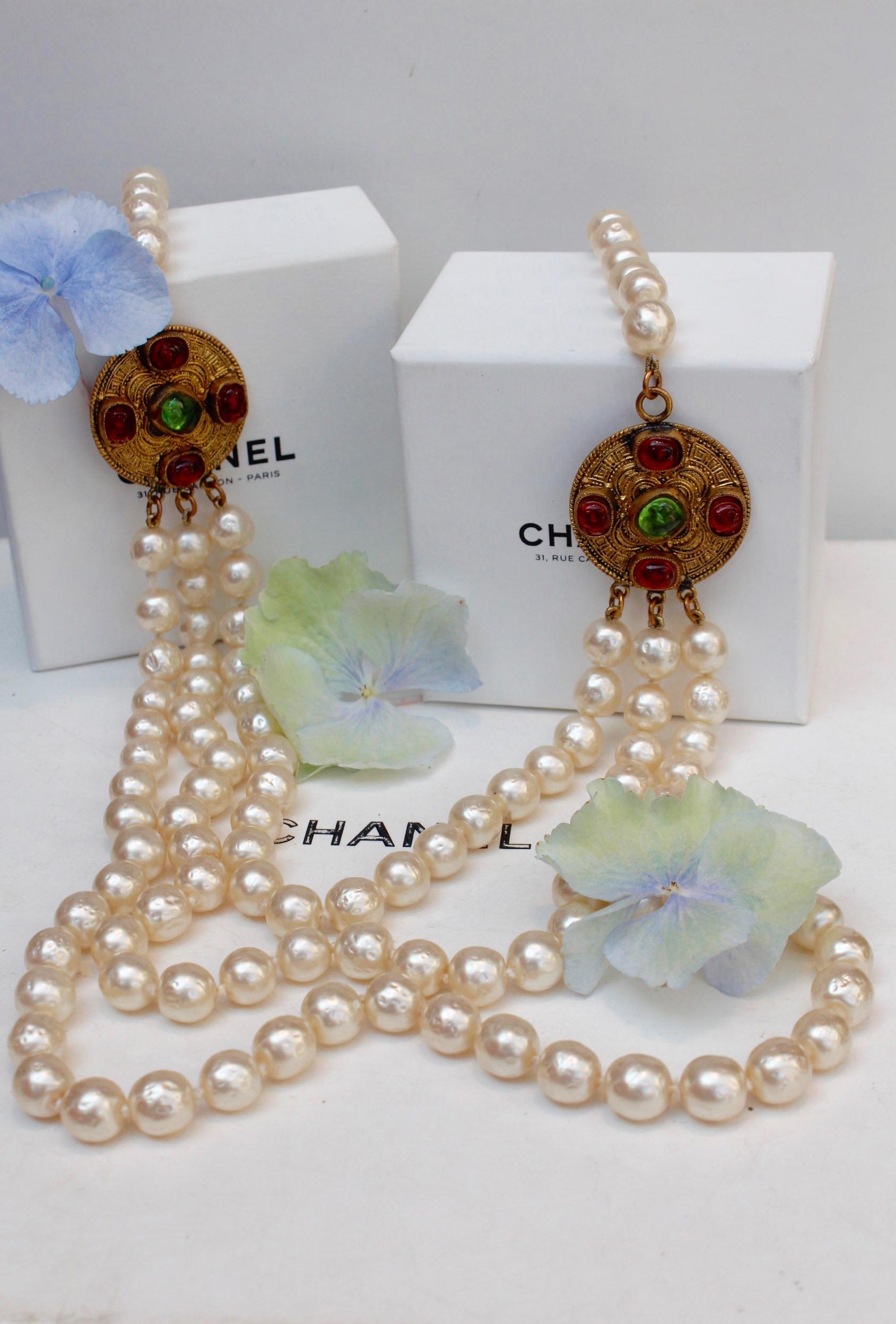 CHANEL (Made in France) 

Beautiful long necklace composed of tree row of baroque faux pearls linked with Byzantine gilted metal elements, adorned with green and red glass paste cabochons. Depending to your waist and hips size, you can also wear it
