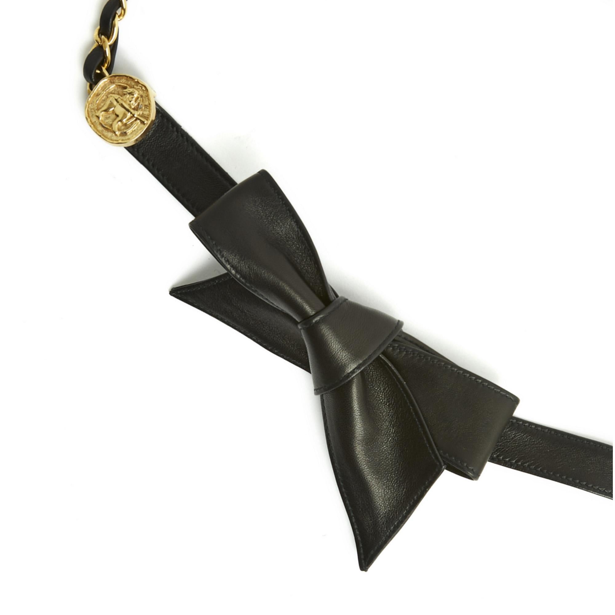 Cinturón Chanel circa 1988 compuesto por una cadena entrelazada de cuero negro prolongada, en cada extremo, por un medallón decorado con una figura inspirada en la mitología y una larga banda de cuero negro, para atar. Longitud total del cinturón