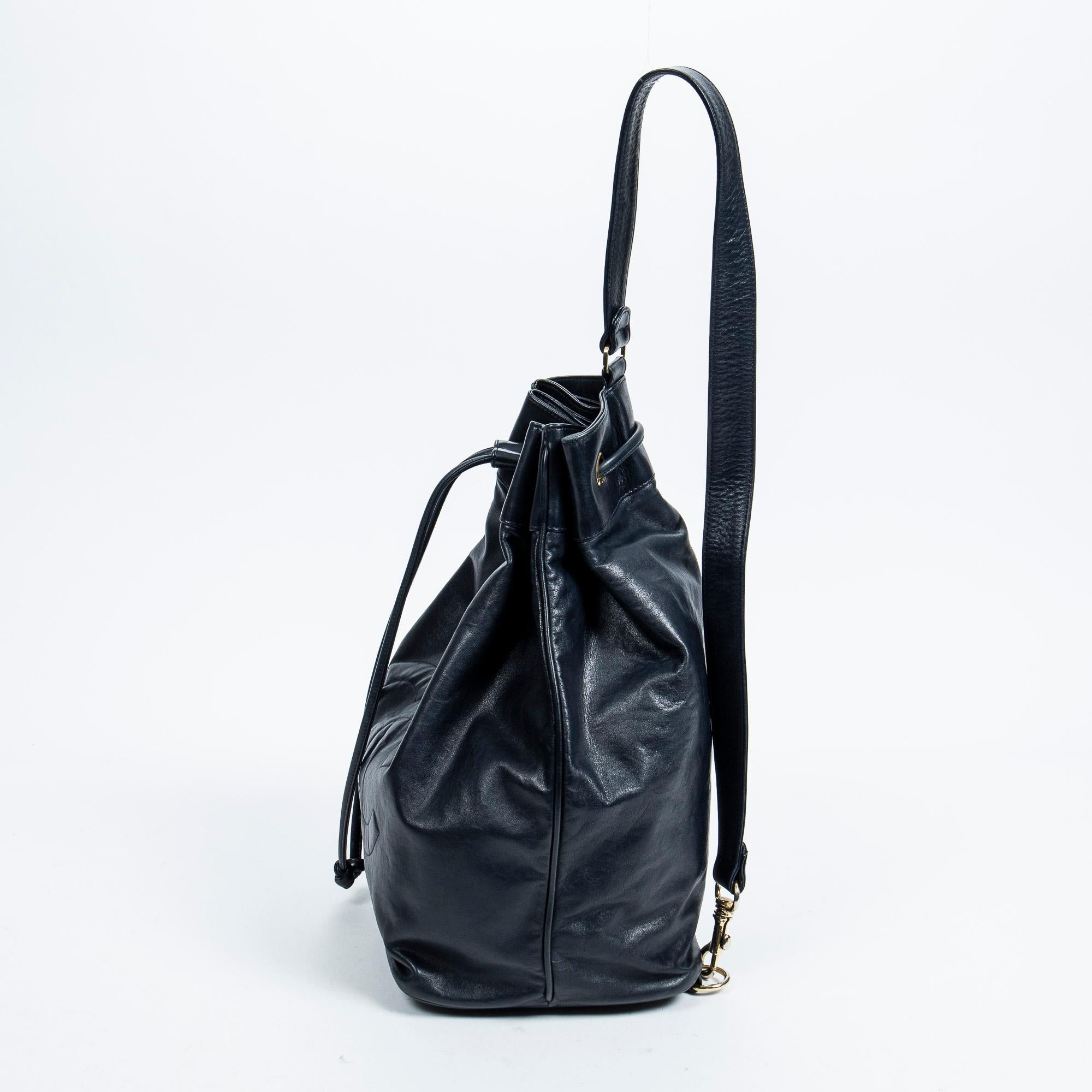 Introducing the Chanel Navy Vintage CC One Shoulder Backpack: a chic companion for urban adventures. Crafted from luxurious lambskin leather in a timeless navy hue, this backpack boasts gleaming gold hardware. Its convenient drawstring closure opens
