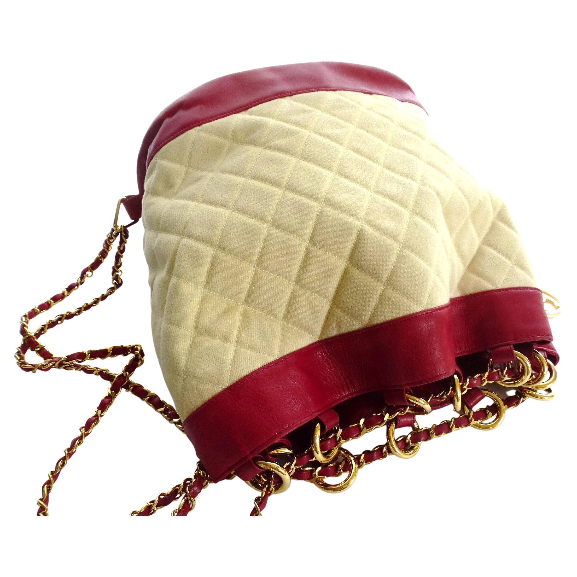 Ikonische Vintage-Umhängetasche von Chanel aus rotem Lammleder und naturfarbenem, gestepptem Canvas. Die lange Tragekette wird durch 12 große vergoldete Ringe an der Oberseite geführt und verschließt so die Tasche. 
Das Innere der Tasche ist