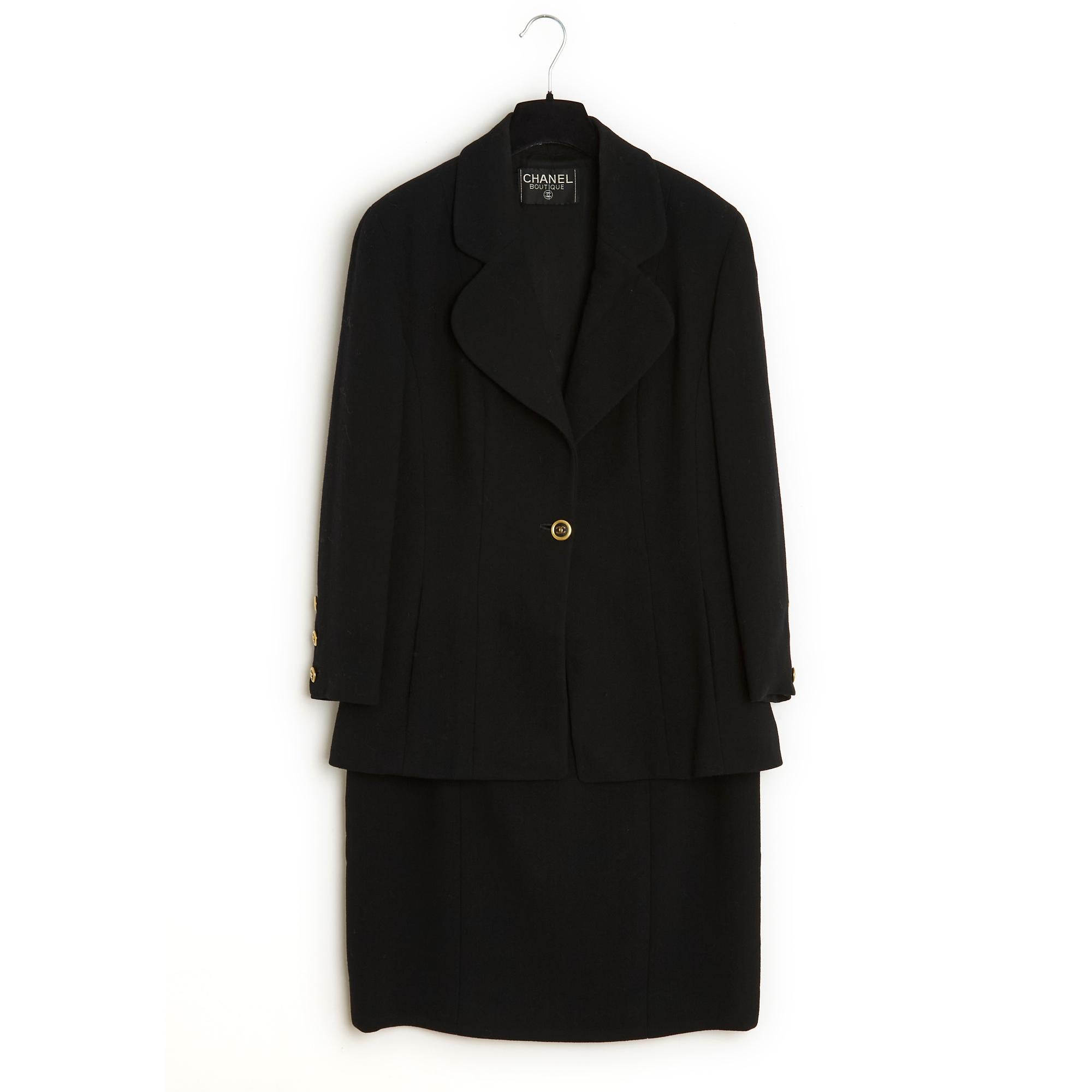 Completo Chanel giacca e gonna fine 1980, in crêpe di lana nera, composto da una giacca con collo arrotondato e dentellato chiuso da un bottone Jewell firmato CC, 2 tasche a fessura e maniche lunghe chiuse da 3 bottoni e una gonna dritta, fodera in