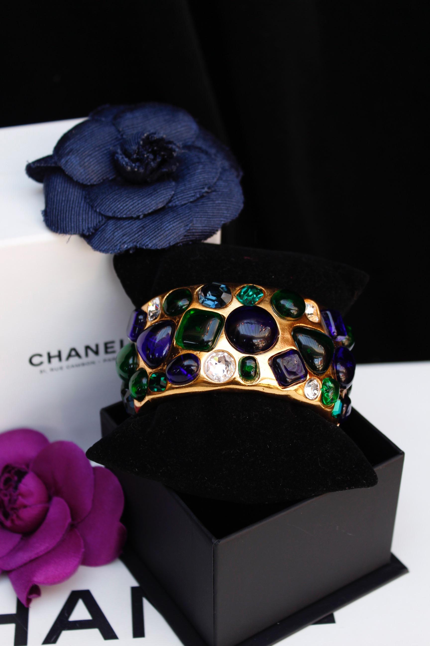 CHANEL (Made in France)
Beautiful and impressive wide gilted metal cuff bracelet adorned by many glass paste cabochons in blue and green colors. It's also decorated by faceted rhinestones in blue, green and white colors.

Signed on a plate at the