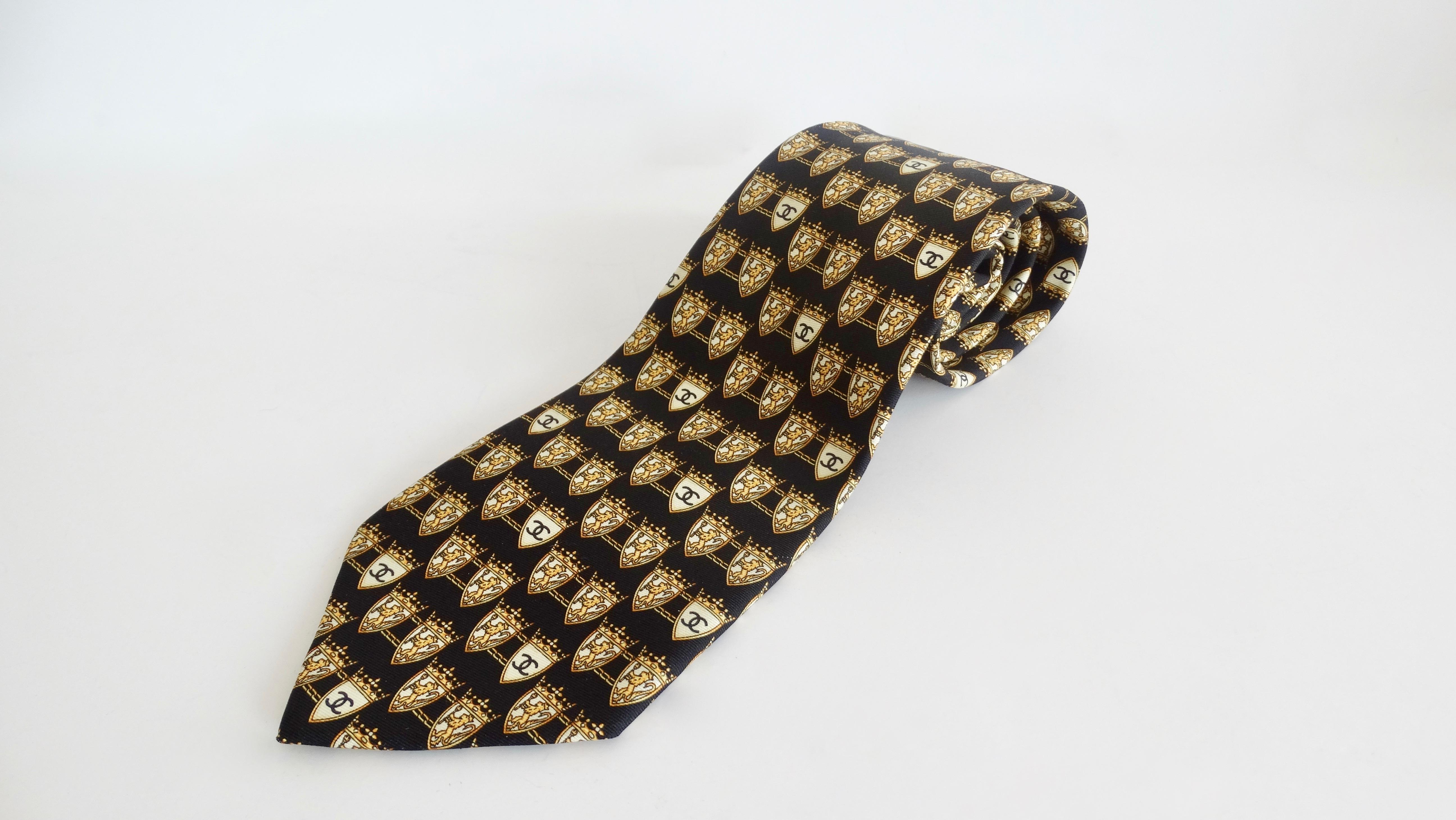 Complete your button up with this Chanel tie! Circa 1990s, this 100% black Silk tie is inspired by Coco Chanel's time in the UK and of course pays homage to her Leo astrological sign. Features an all over pattern of royal crests complete with a lion