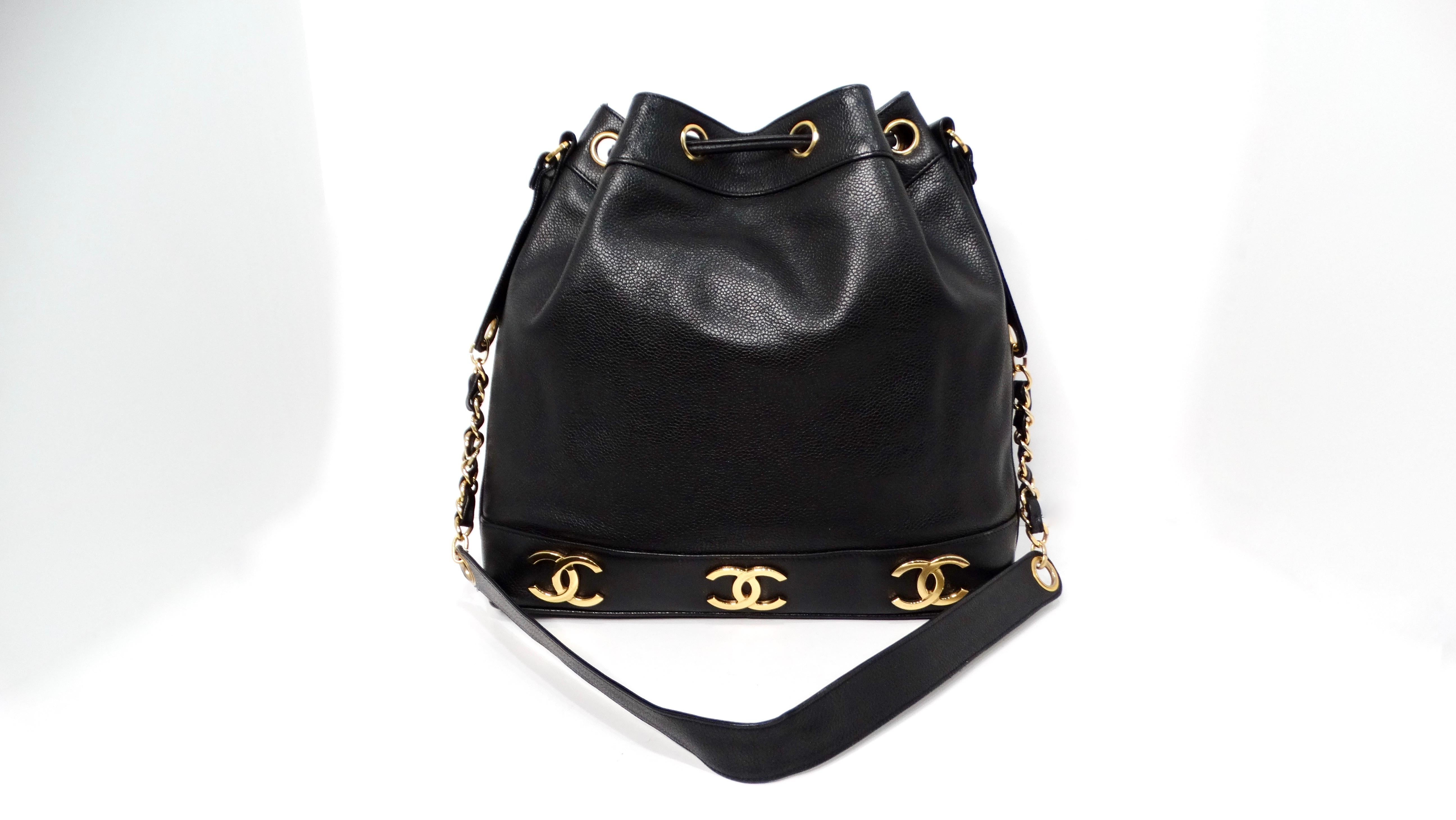 The Chanel 1992 Black Caviar Leather Triple Interlocking CC Drawstring Shoulder Bag is a timeless piece that embodies sophistication and luxe craftsmanship. Crafted from sumptuous black caviar leather, this bag features large gold-tone interlocking