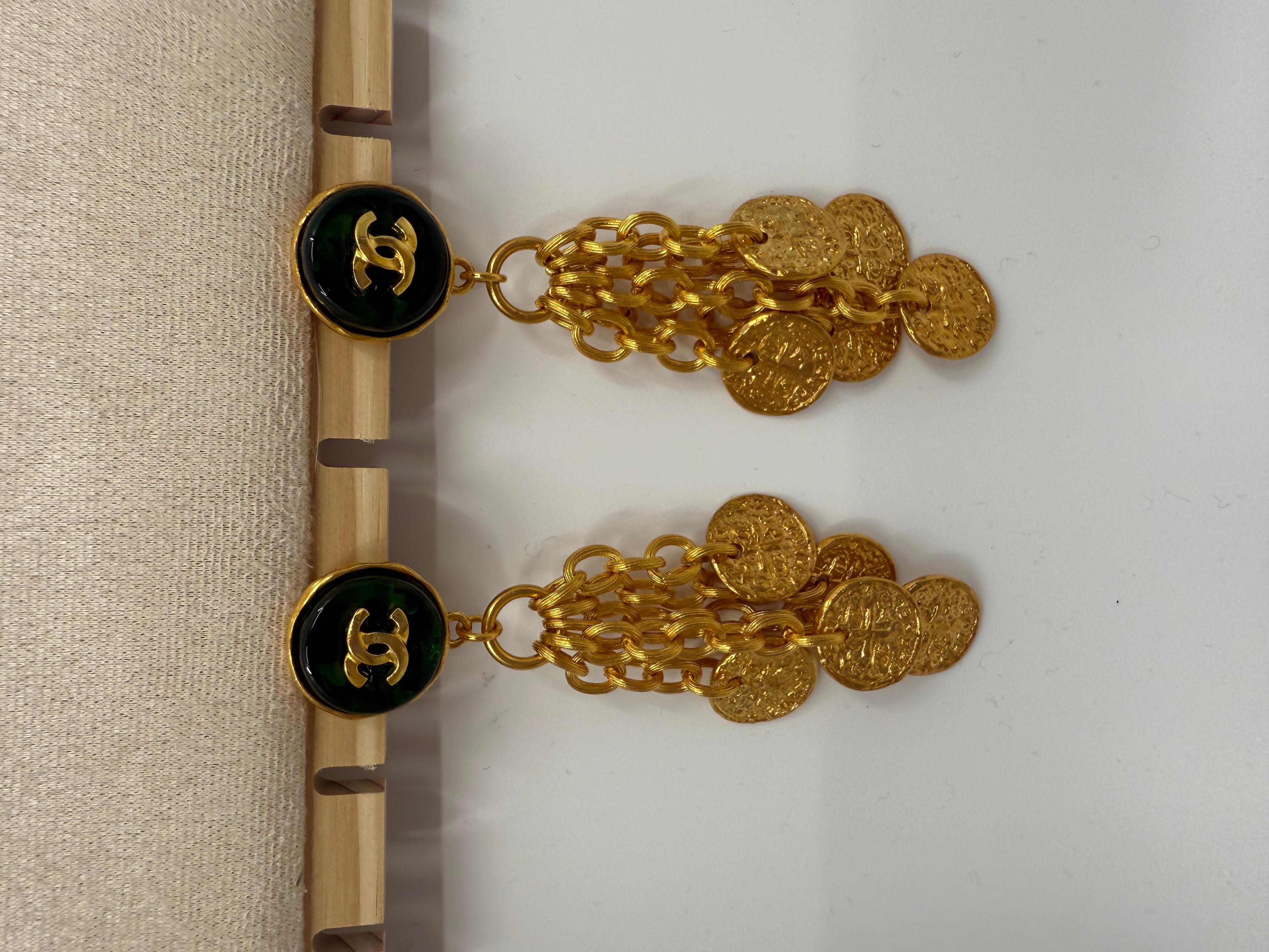 Questi orecchini Chanel della primavera 1993 incarnano la miscela di opulenza e drammaticità tipica della Maison. Caratterizzato da un piano rotondo in vetro colato verde Greene & Greene ornato da un logo CC in rilievo in tonalità dorate, il design