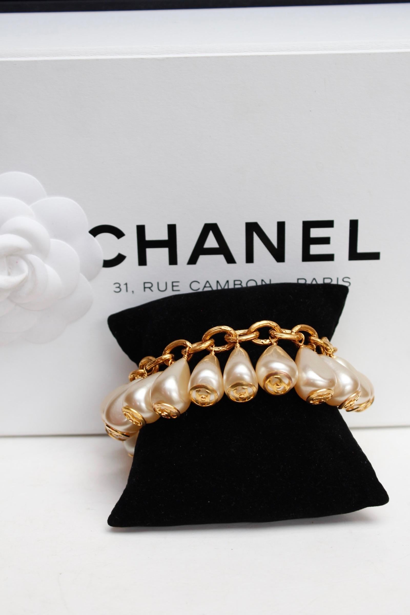 CHANEL (Made in France)
Lovely gilted metal chain bracelet adorned by faux pearly drops elements along its length. Each drop is decorated by an openworked gilted metal circle centered by a CC logo .

Signed on a plate, affixed on a drop, next to the