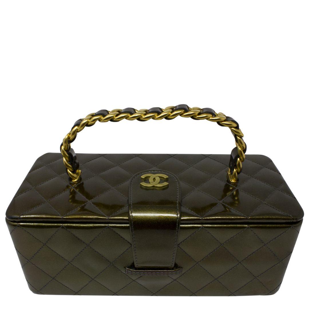 Vintage 1994 limited edition collector's piece! This beauty is crafted in olive green quilted patent leather, a chain-link leather threaded top handle, and CC logo to the top. The snap closure opens to a black leather lining, mirror and one slip