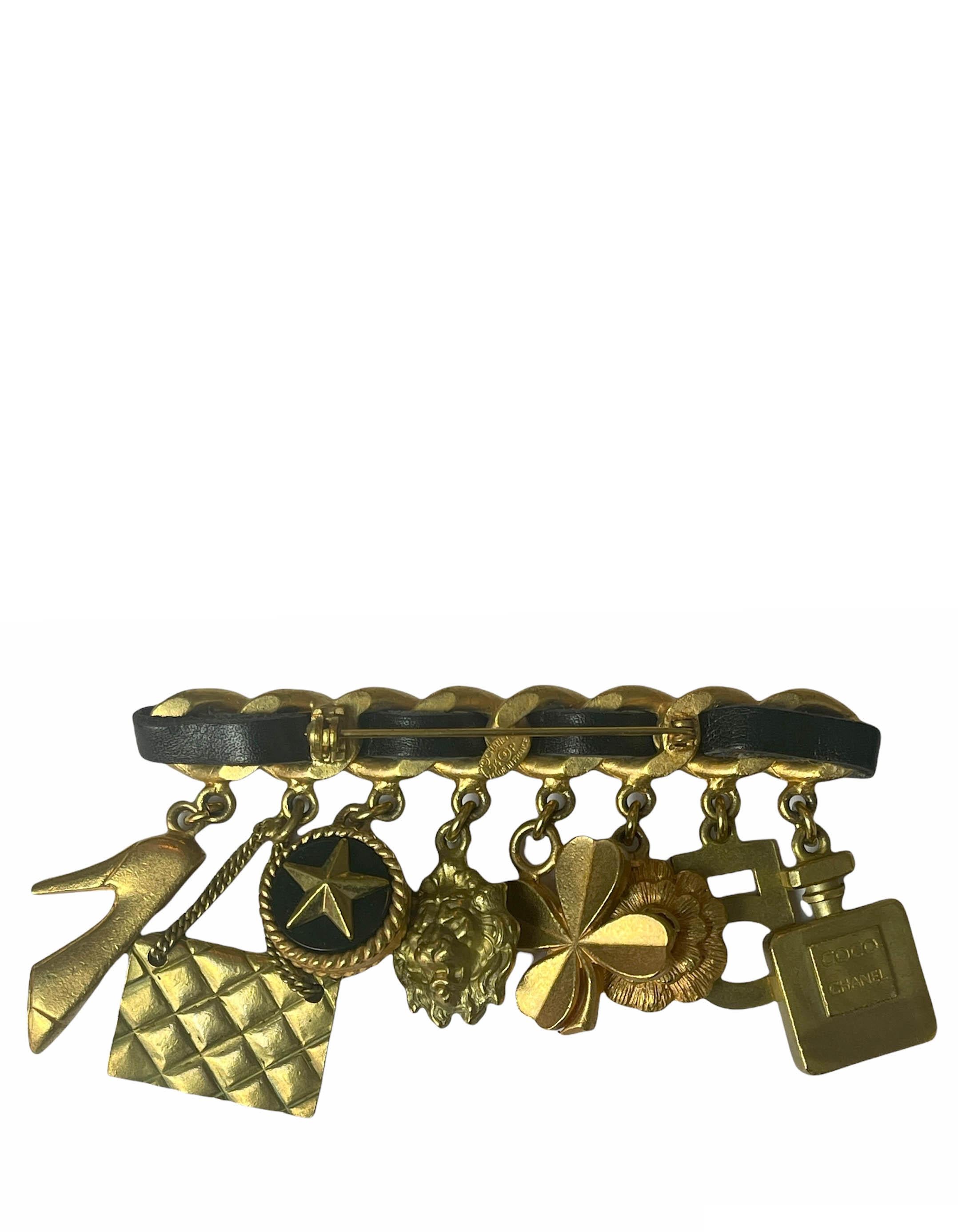 Chanel 1994 Iconic Leather Laced Charm Brooch.  Features Coco Chanel perfume bottle, shamrock, camellia, lion head, quilted bag, high heel, number five, and star charm.

Made In: France
Year of Production: 1994
Color: Goldtone and black
Materials: