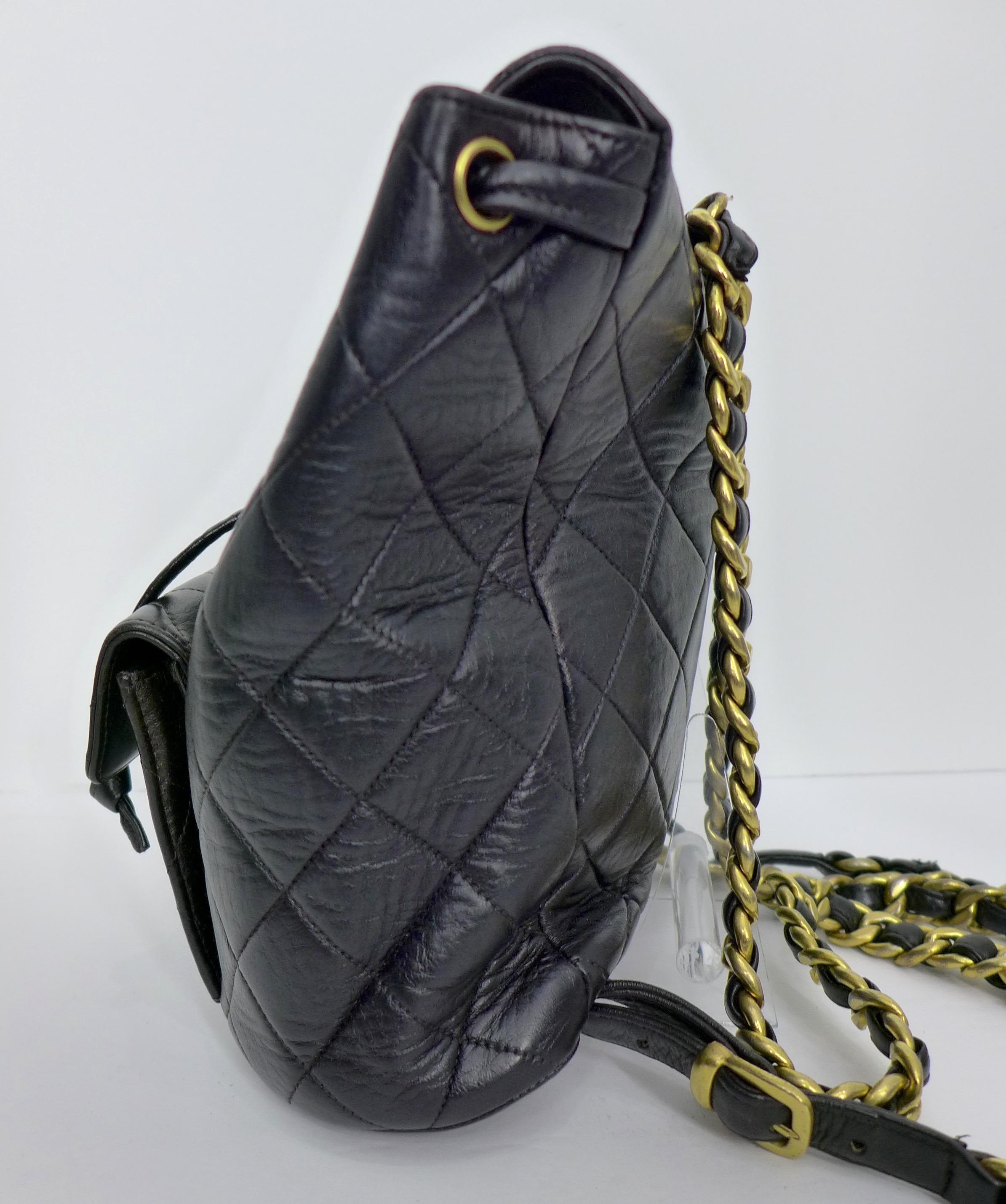 This 1995 Chanel black quilted leather backpack features gold logos, closures, and braided chain straps.  The bag has a front wallet pocket and a leather drawstring tie. 

Measurements in Inches:
Length: 10.5 
Width: 4
Height: 8.5 
Wallet Pocket: 5