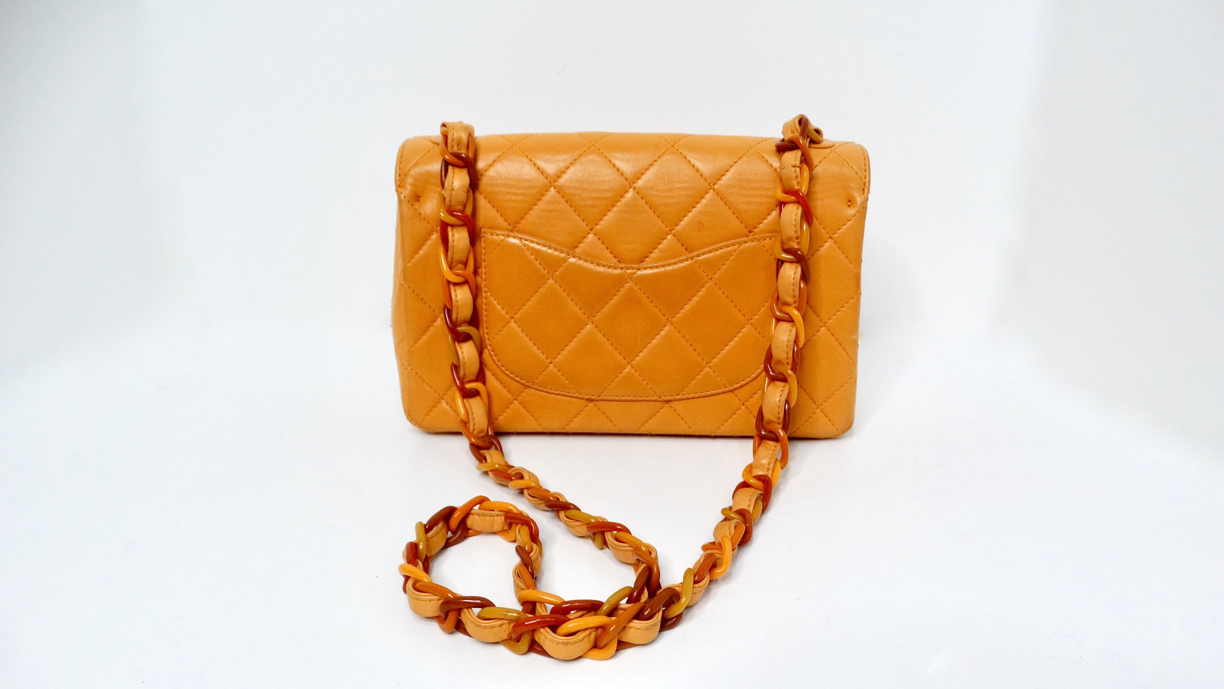 The Chanel 1996 Orange Carmel Lambskin Quilted Single Flap Bag with Lacquer Chain is a striking piece that exudes playful elegance and vibrant charm. Crafted from sumptuous soft lambskin leather in a rich orange hue, this bag stands out with its