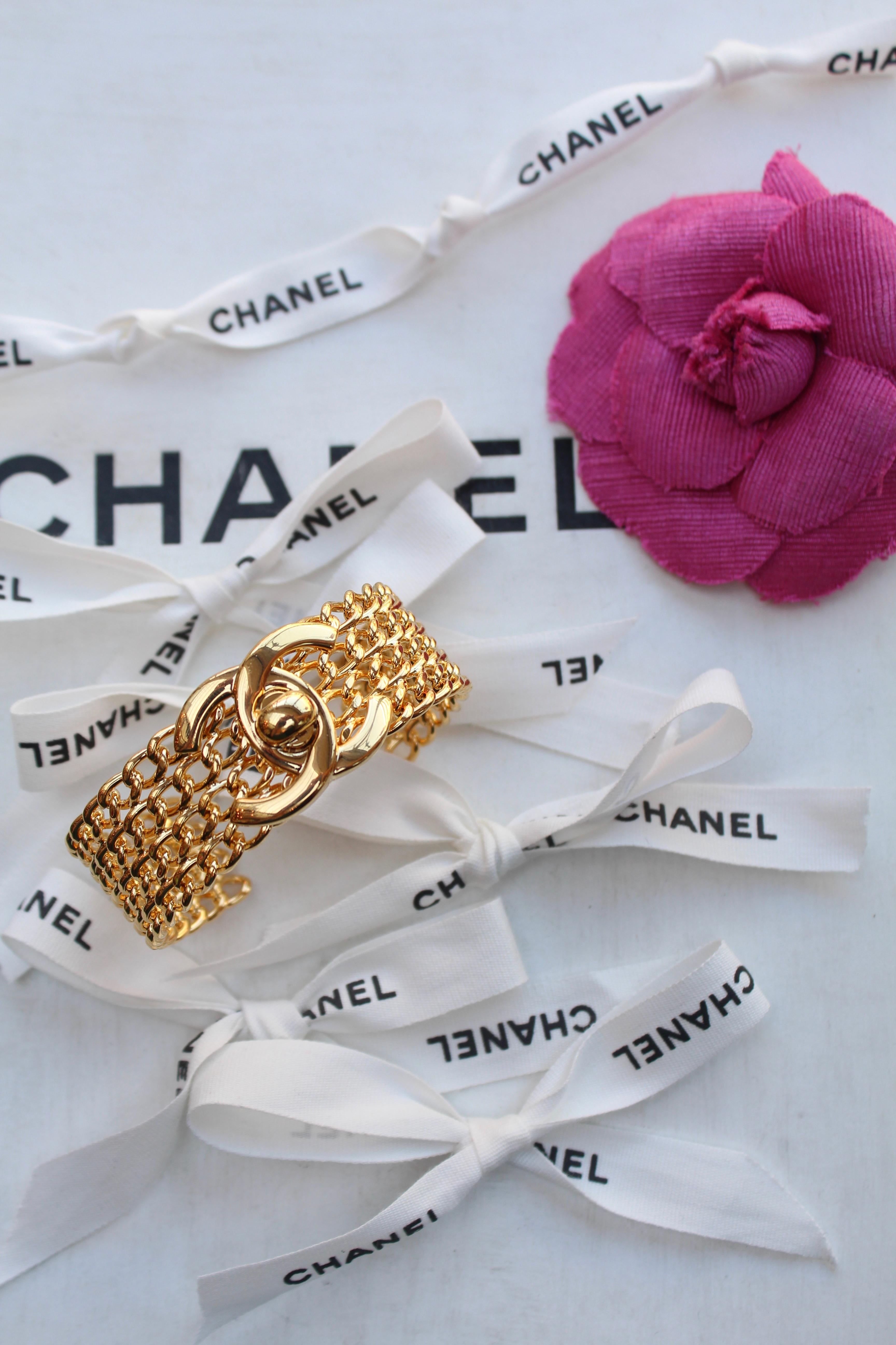 CHANEL (Made in France) 
Wide cuff comprised of four strands of gilted metal curb chain. It is decorated in the center with a twist-lock logo, an iconic emblem of the brand in the 1990’s, also used as a clasp on every “Timeless” bag.

1996