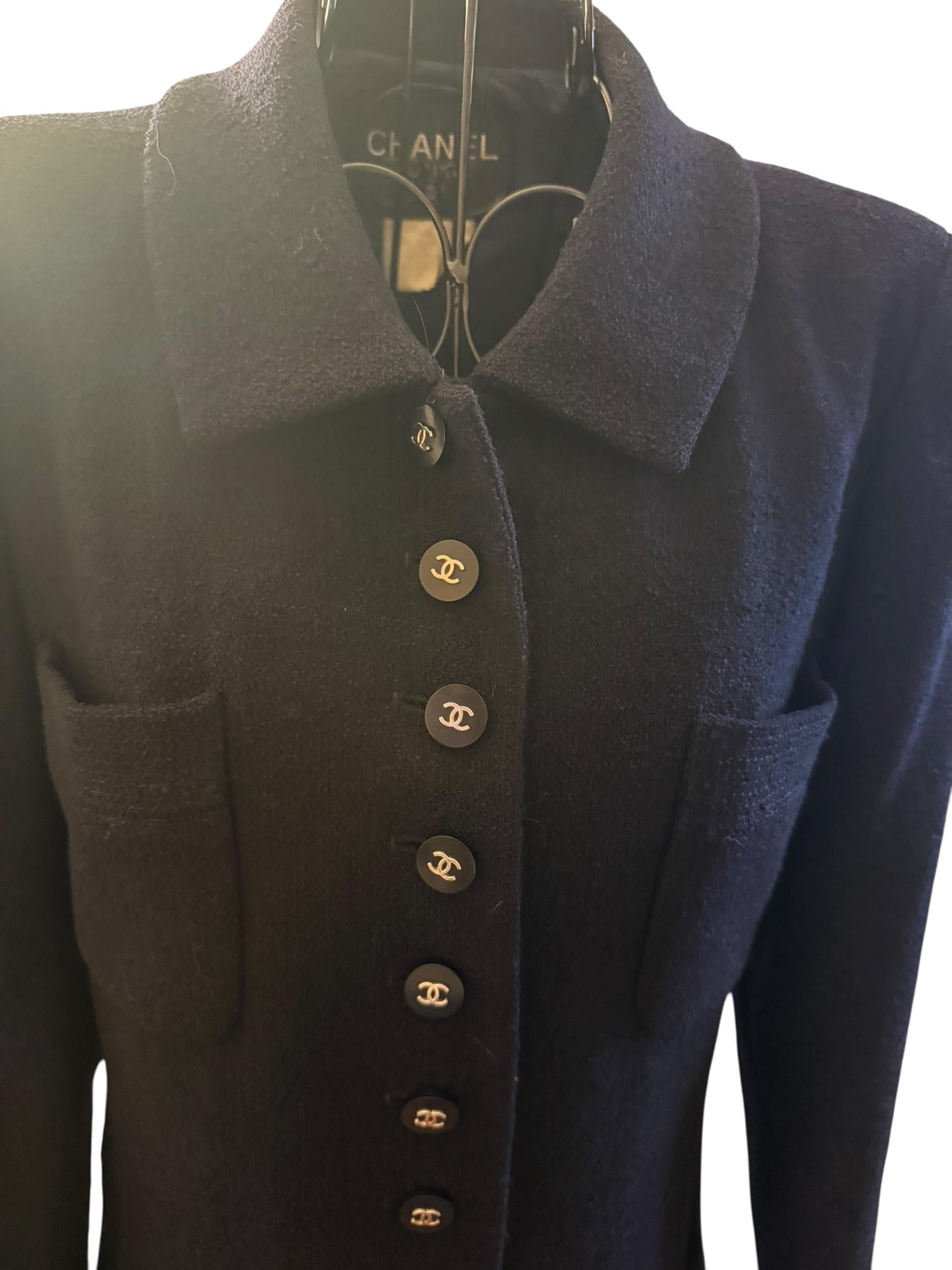Questa elegante giacca longilinea blu appartiene alla collezione Chanel 1996, nota per la sua sartoria raffinata e i suoi dettagli iconici. Realizzato in lussuoso bouclé di lana, presenta un'impressionante serie di 13 bottoni CC dorati sul davanti,