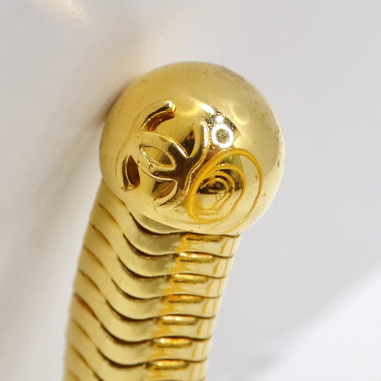 Wir präsentieren die außergewöhnliche Chanel 1997 Gold Tone Spiral Arm Cuff, ein seltenes Vintage-Stück, das zeitlose Eleganz und Raffinesse ausstrahlt. Dieses mit viel Liebe zum Detail gefertigte, vergoldete Spiralarmband/Armreif ist ein
