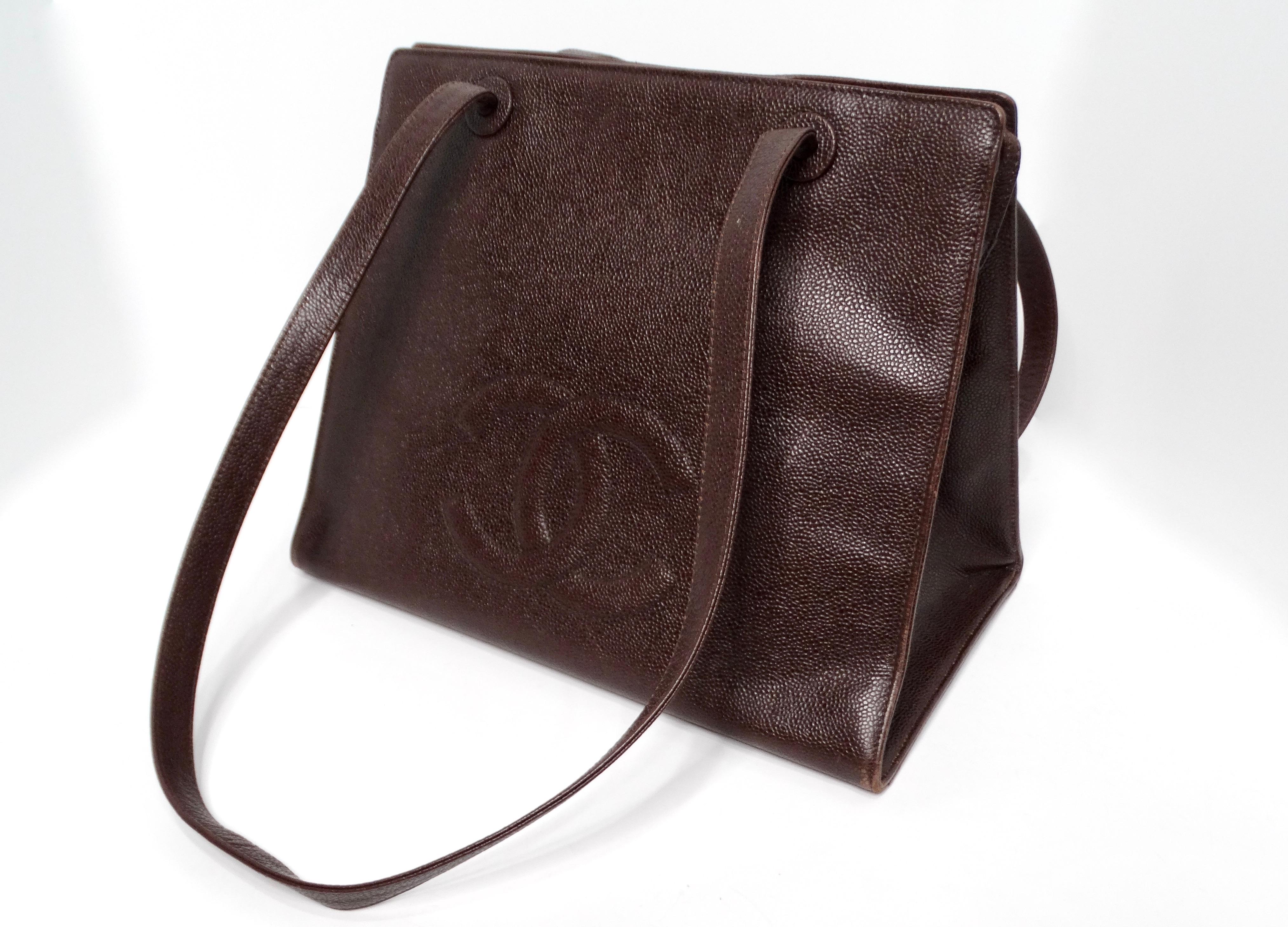 The Chanel 1998 Brown Caviar Leather Interlocking CC Logo Timeless Tote Bag is a sophisticated addition to any luxury collection. Crafted from deep burgundy brown caviar pebbled leather, this tote exudes timeless elegance while ensuring durability