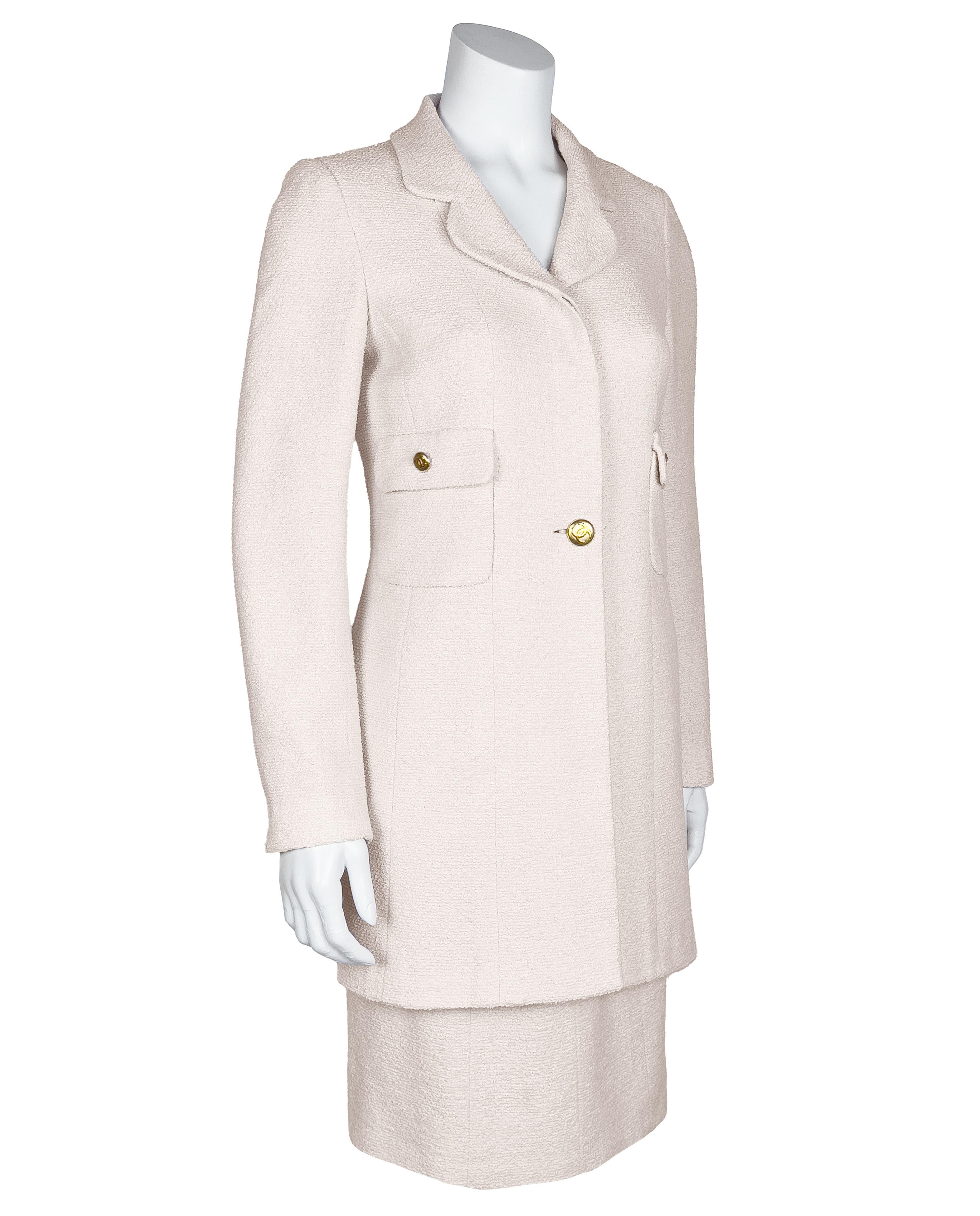 Chanel 1998 Collection S. Costume en laine bouclée crème avec jupe en forme de crayon et veste à simple boutonnage de longueur équestre. Le col cranté légèrement arrondi se termine par un bouton en métal doré portant le logo CC. Plaquette cachée 