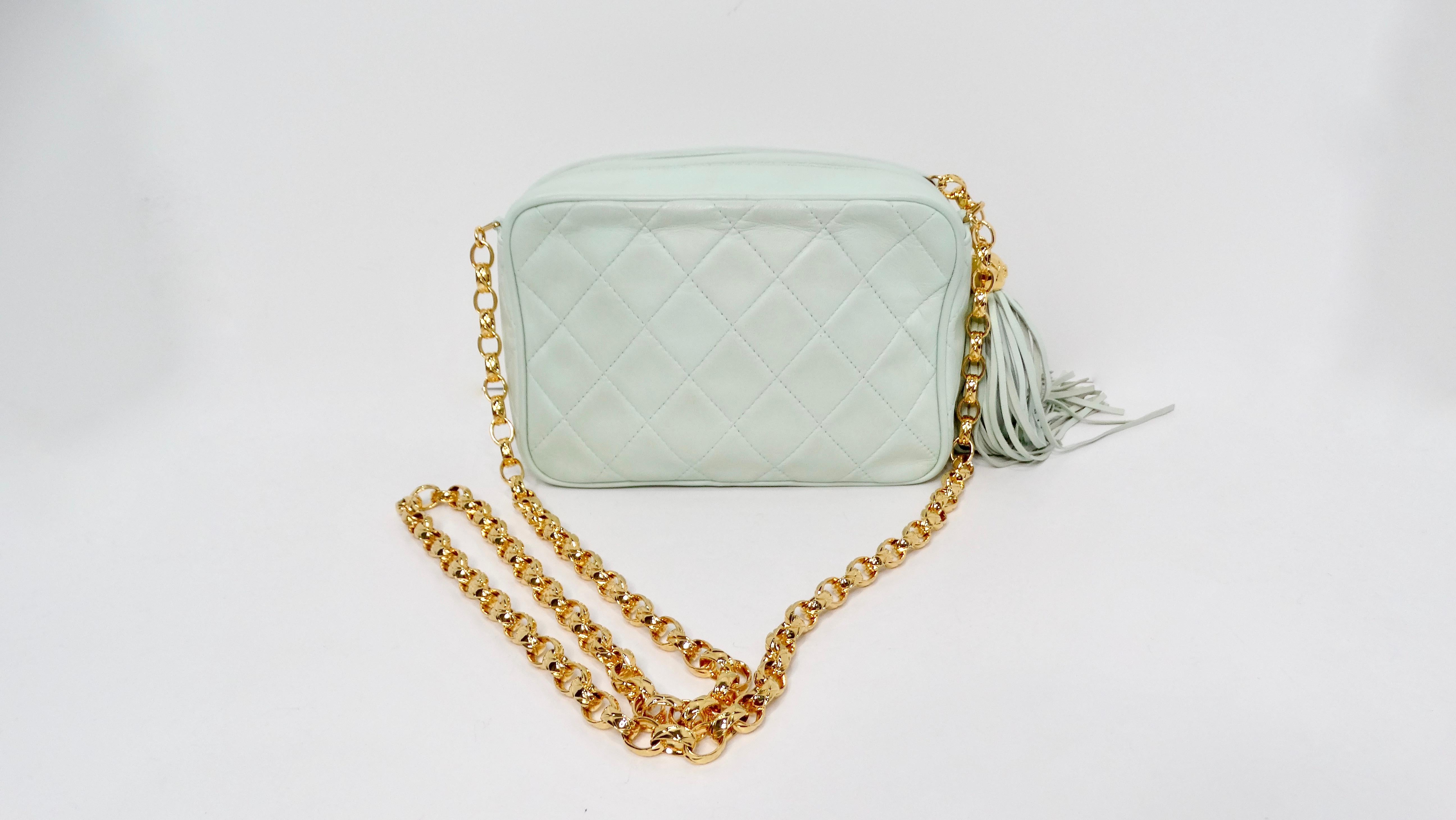 The Chanel 1998 Mint Quilted Lambskin Crossbody Camera Bag with Tassel is a stunning representation of vintage luxury blended with practical function. Crafted from soft mint green lambskin, this bag features a chic quilted design that is both