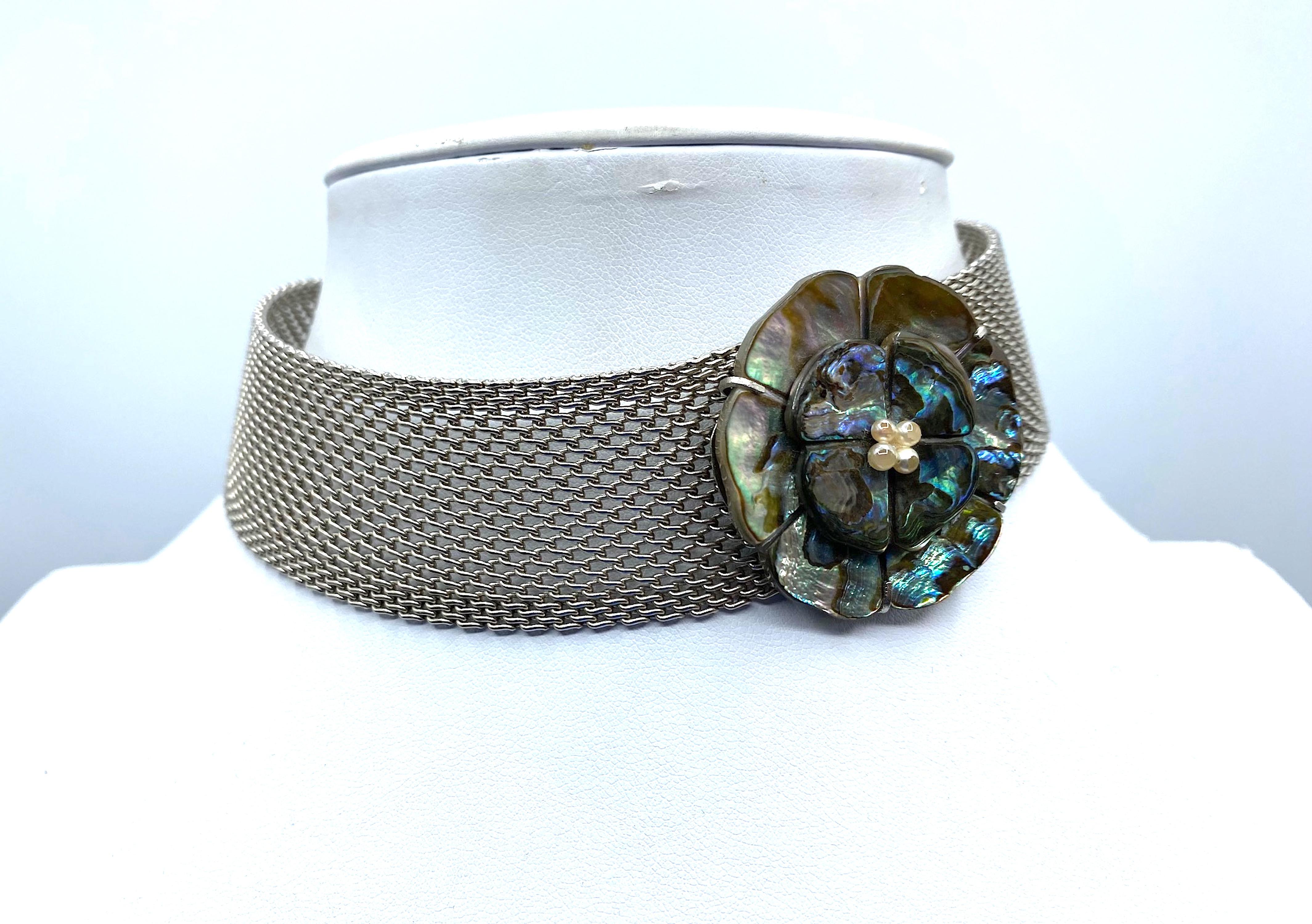 Questa collana Chanel della collezione 1998 è un pezzo distintivo ed elegante che esemplifica l'impegno del marchio per la qualità e l'innovazione del design. Con l'uso unico dell'abalone e l'accento decentrato del fiore di camelia, riflette la