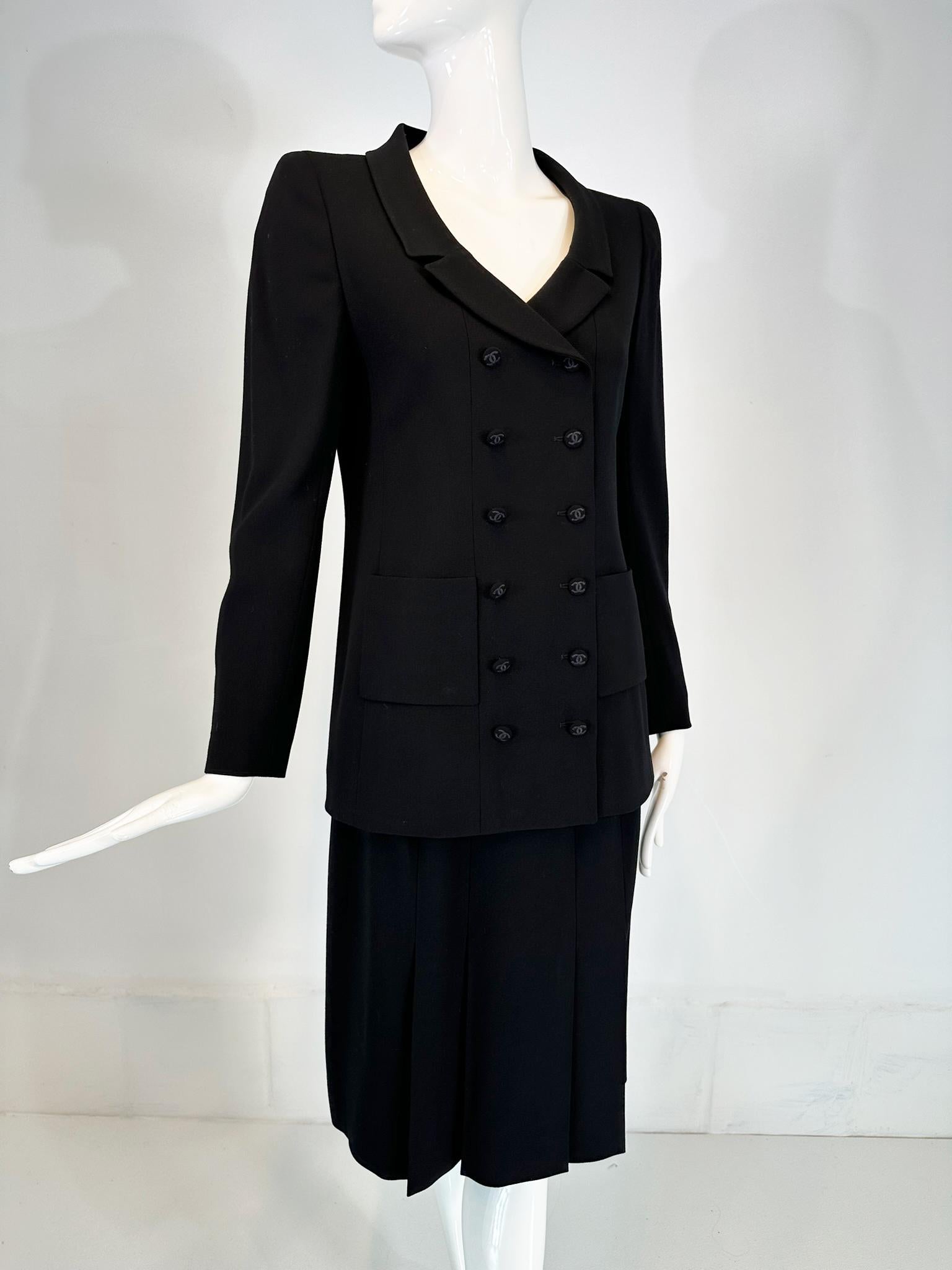 Chanel Boutique 1998P black 100% wool double breasted jacket & pleated skirt set, marked size 36. Beautiful fine black wool suit, the hip length jacket is double breasted with embroidered Chanel logo buttons. Open rounded neckline with narrow