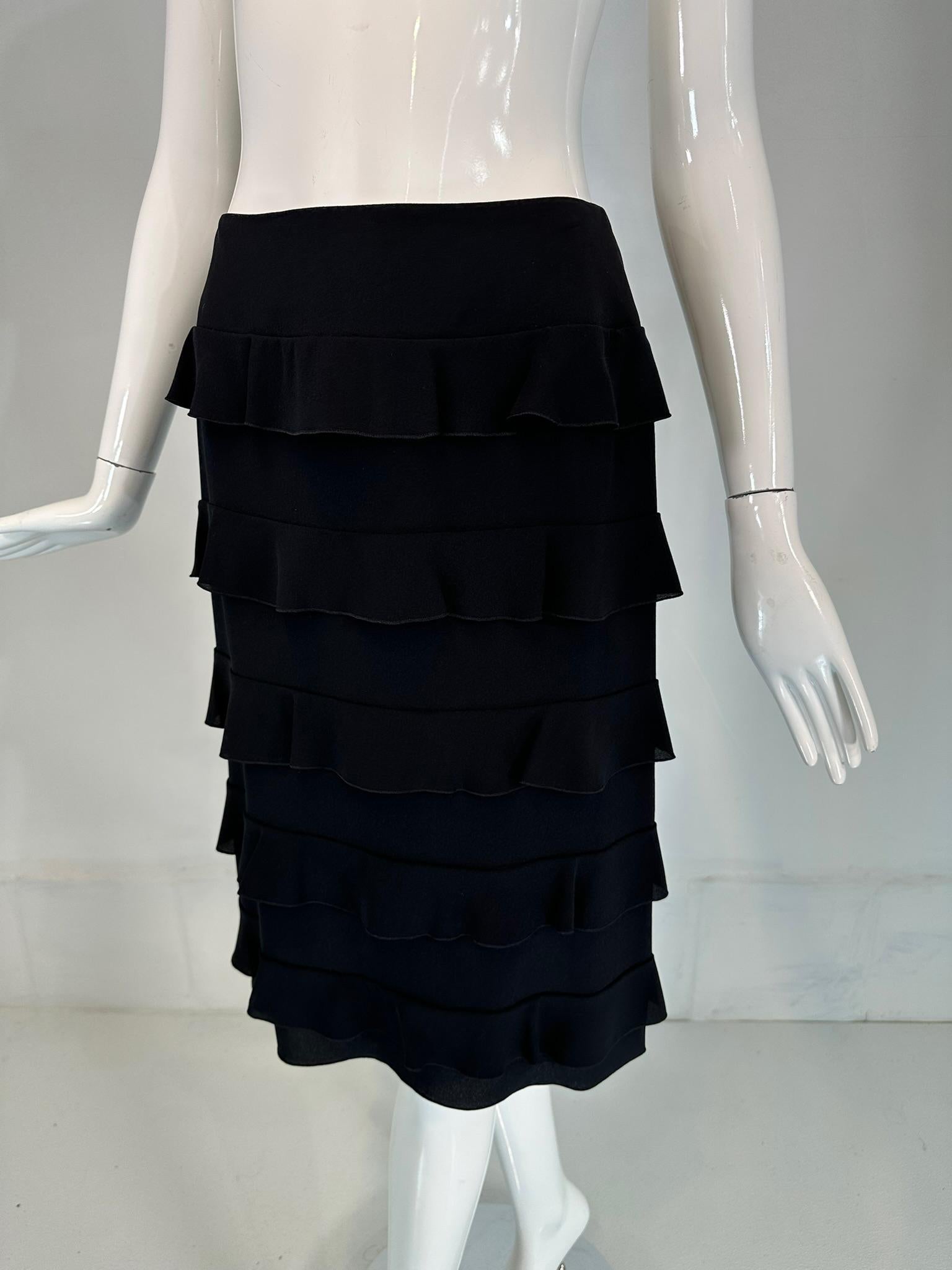 Chanel 1999a Black silk tiered ruffle skirt marked size 36. Seamed waist skirt closes at the back with two Chanel logo buttons at the waist and a hidden zipper. The skirt has layers of ruffles from hip top to hem. Fully lined. 
In very good pre