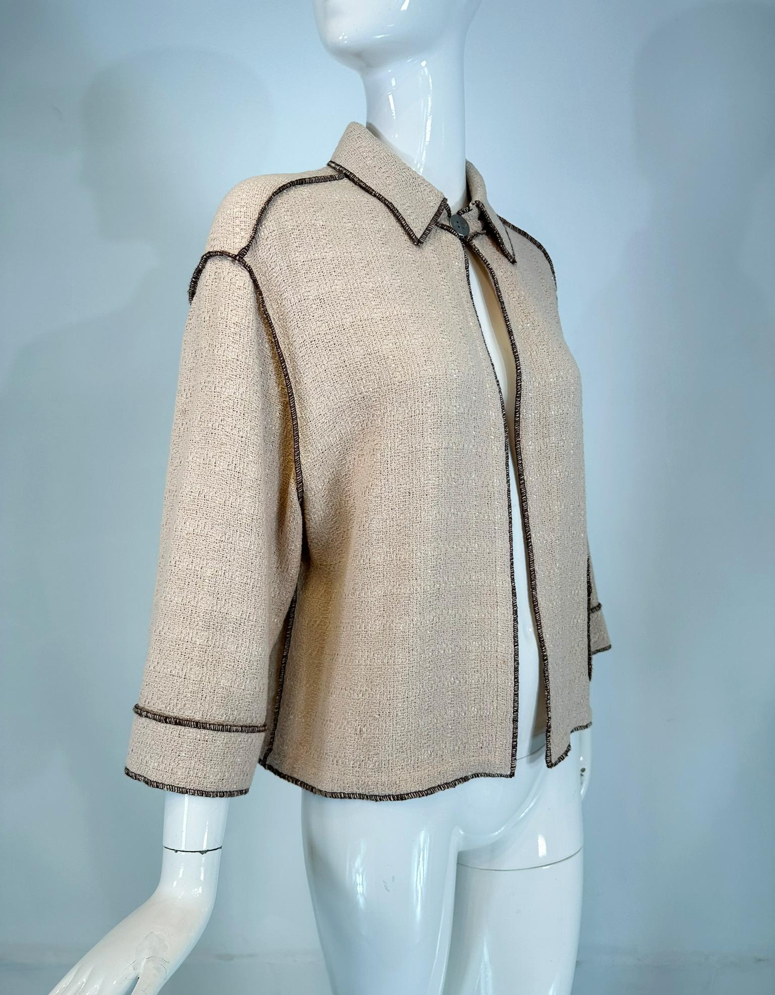 Chanel, veste ouverte en coton beige et marron à armure serrée  tissé avec un subtil quadrillage. Point de recouvrement marron sur l'ensemble de la pièce. Col étroit, fermeture à crochet avec logo en métal argenté mat à l'encolure. Dos à