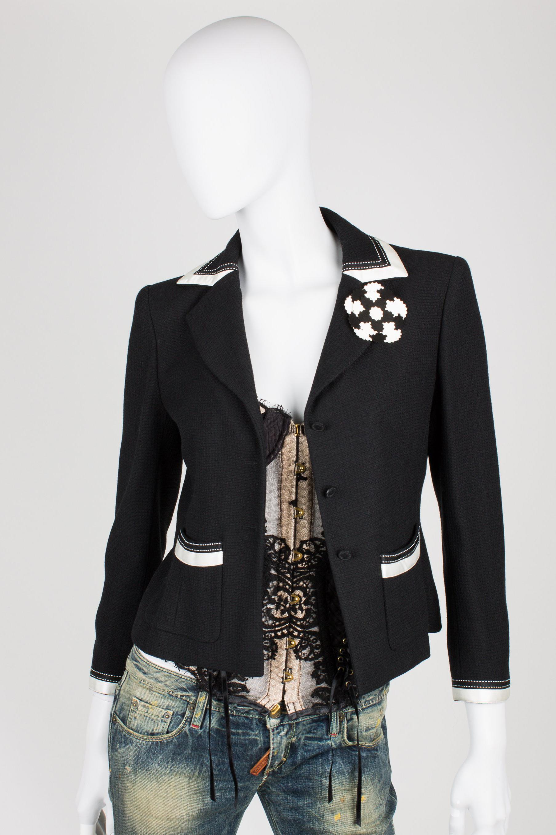 Beautiful black and white Chanel suit; a blazer and a skirt

The blazer is made of black fabric with white satin trimming. Black coin buttons at the front, three in a row. At the end of the sleeves also three of these buttons, a little bit smaller