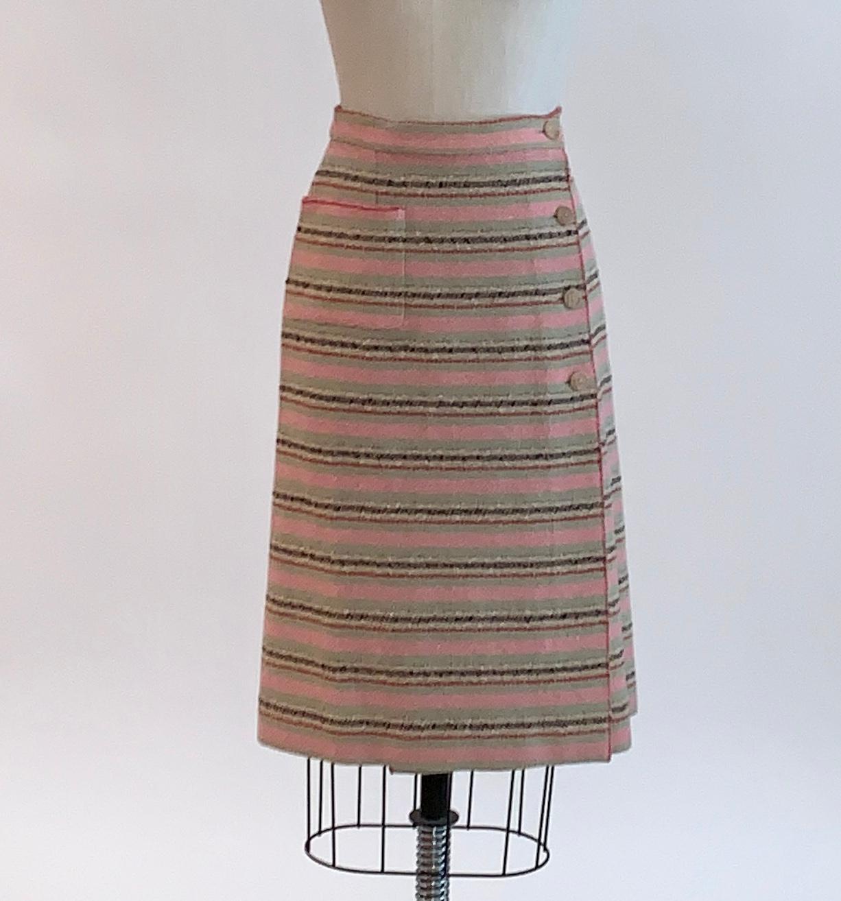 Chanel tweed pencil skirt in muted pink, sage green, natural, and red stripes. Branded 'Chanel, Paris' on wooden buttons at front. Side and back patch pockets. 

80% Wool, 20% Nylon. Unlined.

Made in France.   

Size FR 40, approximate US 8, see