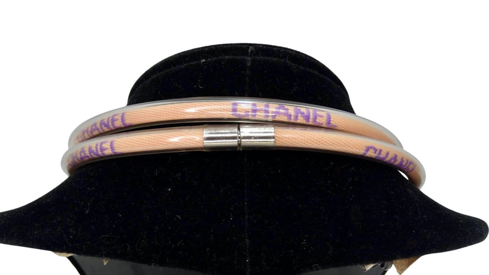 The definition of sporty chic! Circa 2000, this double wrapped rubber tube necklace features a pink vinyl rope stamped with 'Chanel' in purple. Twist closure and stamped is located on the interior. Simple and fun, this necklace is perfect for
