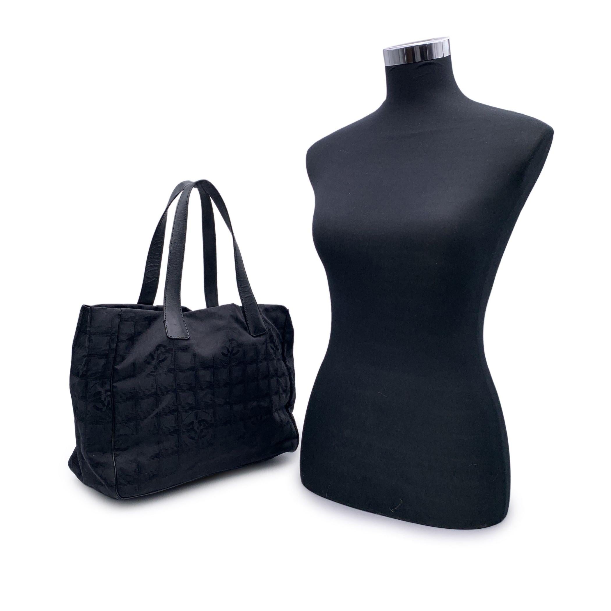 Chanel black jacquard nylon tote bag from the 'Travel line' collection. Period/Era: 2000/2002. Black leather shoulder strap. Nylon lining with 2 side zip pockets inside. 'Chanel - Made in Italy' tag , authenticity hologram tag inside the bag