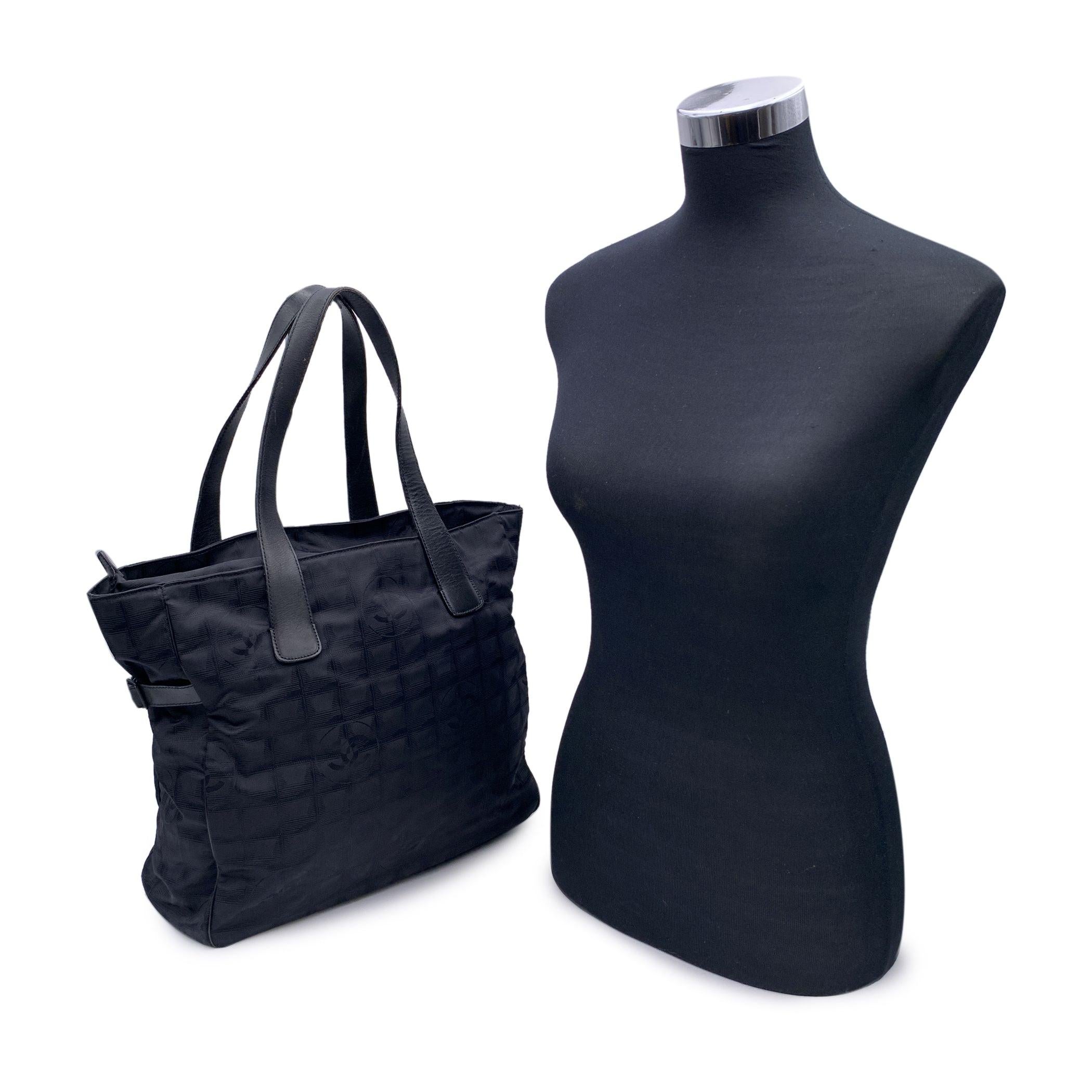 Chanel black jacquard nylon tote bag from the 'Travel line' collection. Period/Era: 2000/2002. Black leather shoulder strap. Nylon lining with 2 side zip pockets inside. 'Chanel - Made in Italy' tag , authenticity hologram tag inside the bag