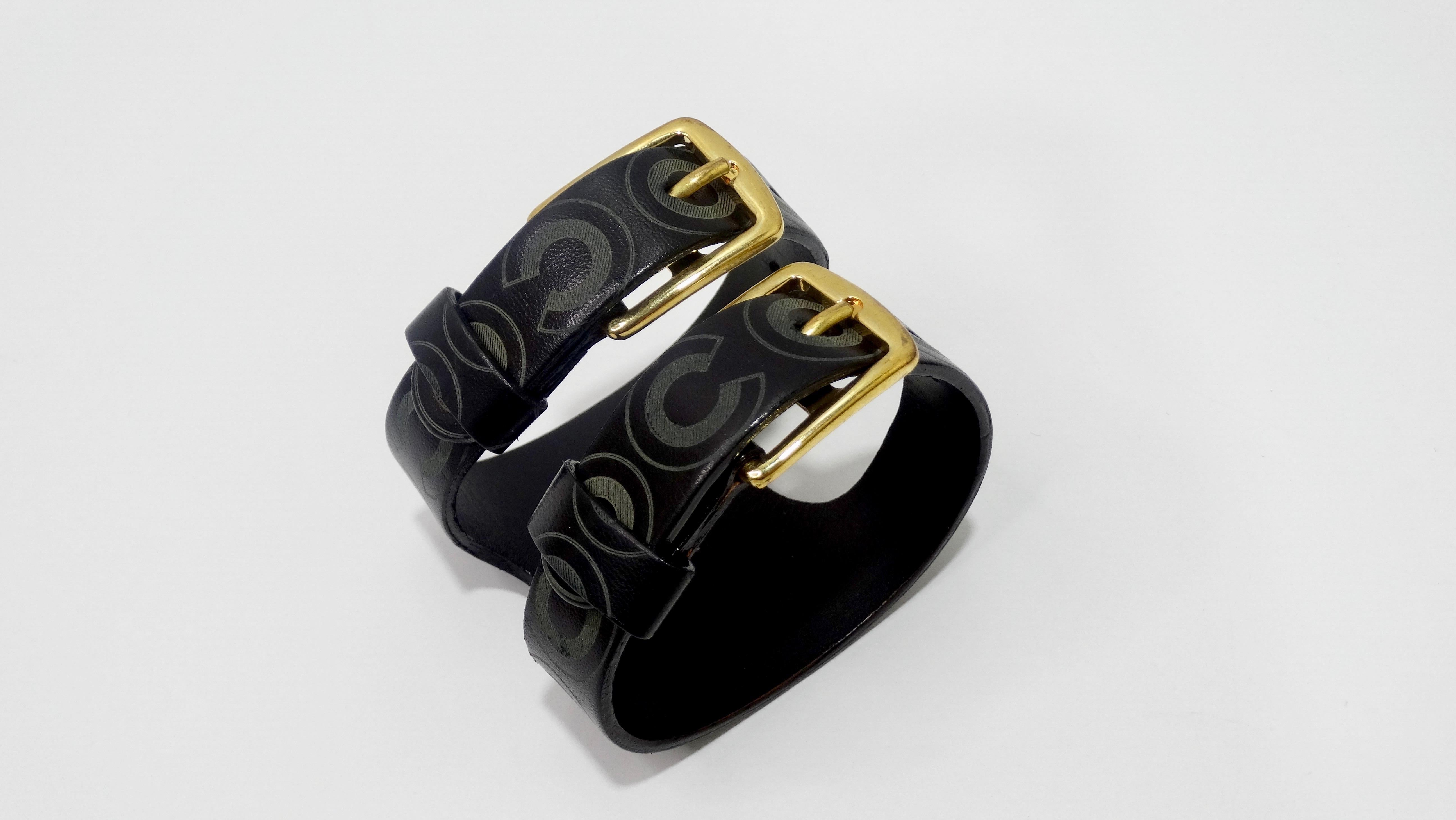 Accessorize your next look with this adorable Chanel cuff! Circa 2001 from their F/W collection, this cuff is crafted from black leather and features 'COCO' in bold grey letters, gold hardware and two adjustable buckle closures. Interior is stamped