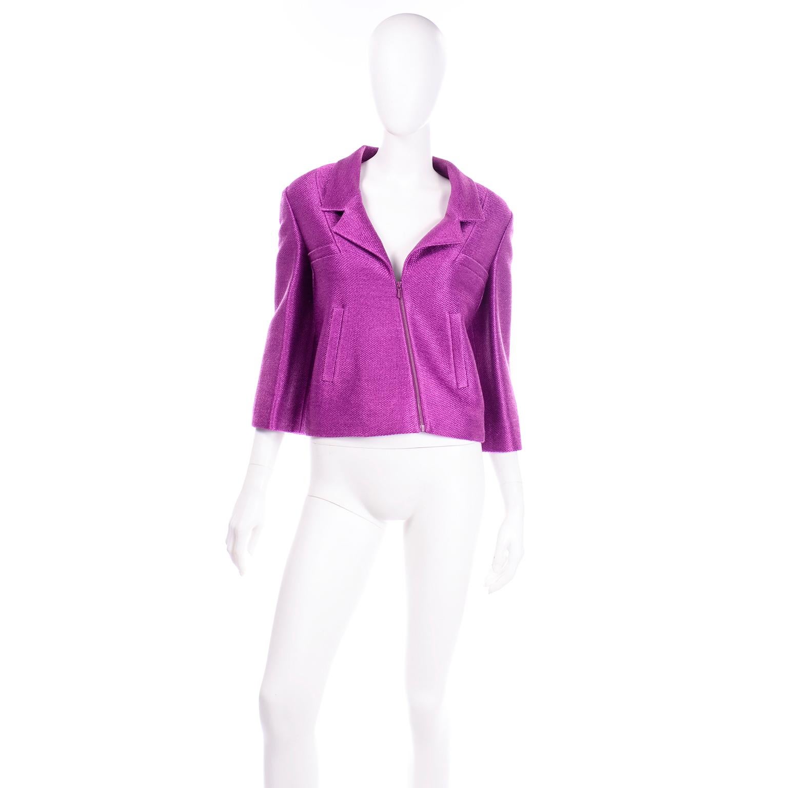 This incredible S/S 2001 vintage Chanel jacket is made from a woven magenta purple cotton blend fabric with a metallic sheen. The jacket and sleeves are slightly cropped and there is a front zipper that is asymmetrical on the bodice. The jacket has