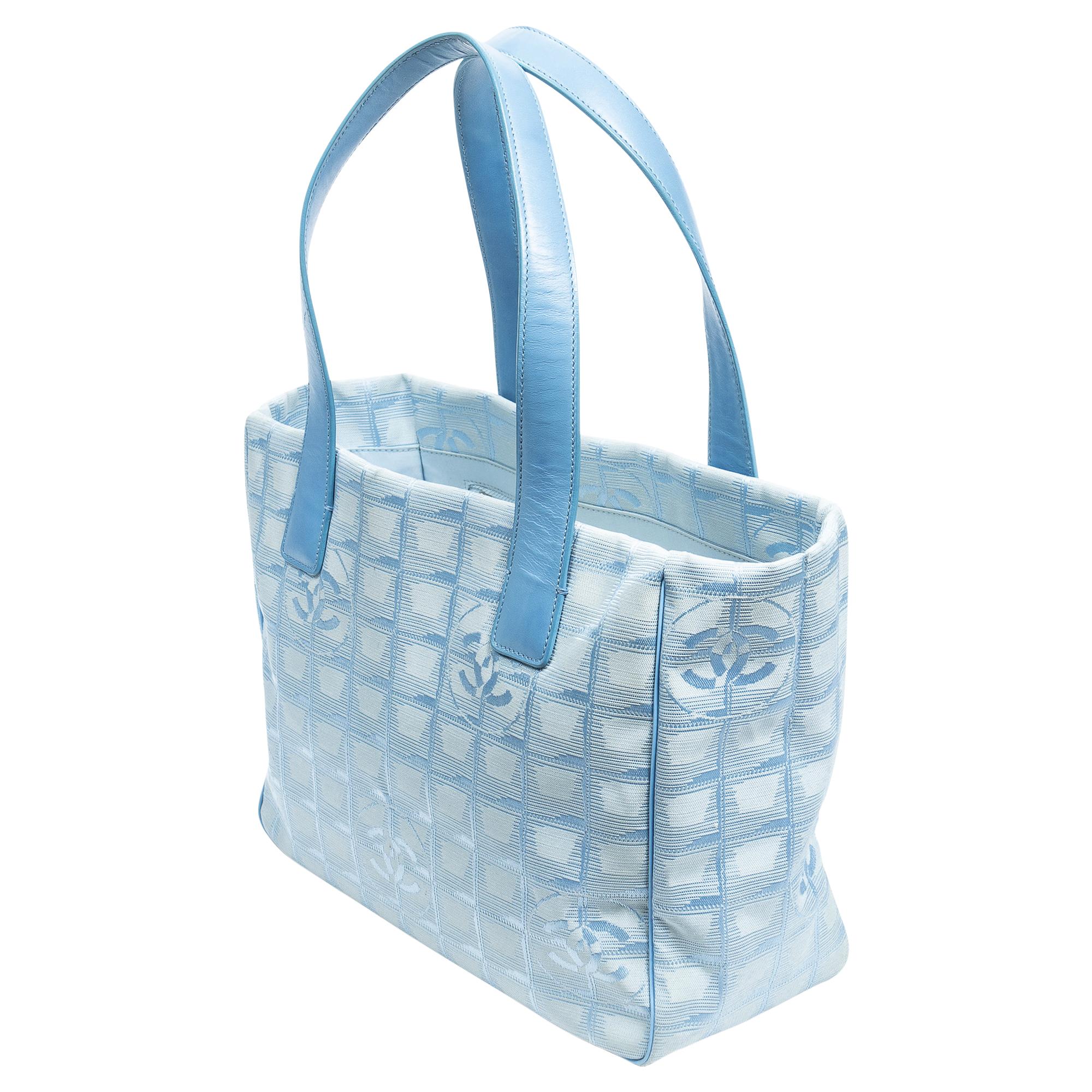 Dive into sophistication with the Chanel 2002 Blue Travel Ligne Shopping Tote. Crafted from durable canvas in a serene blue hue, it's a stylish companion for everyday adventures. Enhanced with silver hardware and a practical zipper closure, its