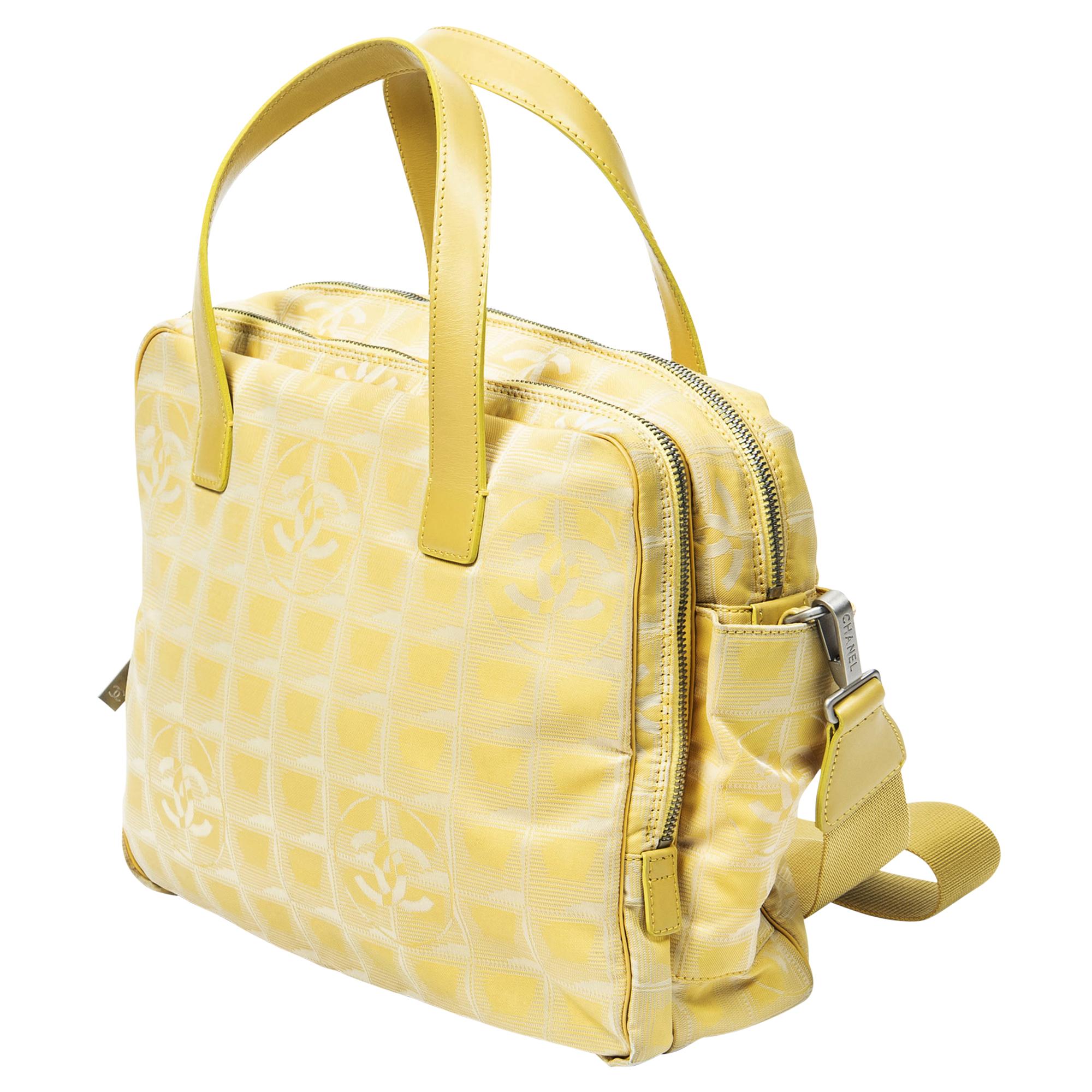 Die Chanel 2002 Yellow Travel Ligne Bag w/ Strap ist ein lebhaftes Accessoire für modebewusste Entdeckerinnen. Aus strapazierfähigem Canvas in einem sonnigen Gelbton gefertigt, strahlt er verspielte Eleganz aus. Die Tasche ist mit silbernen