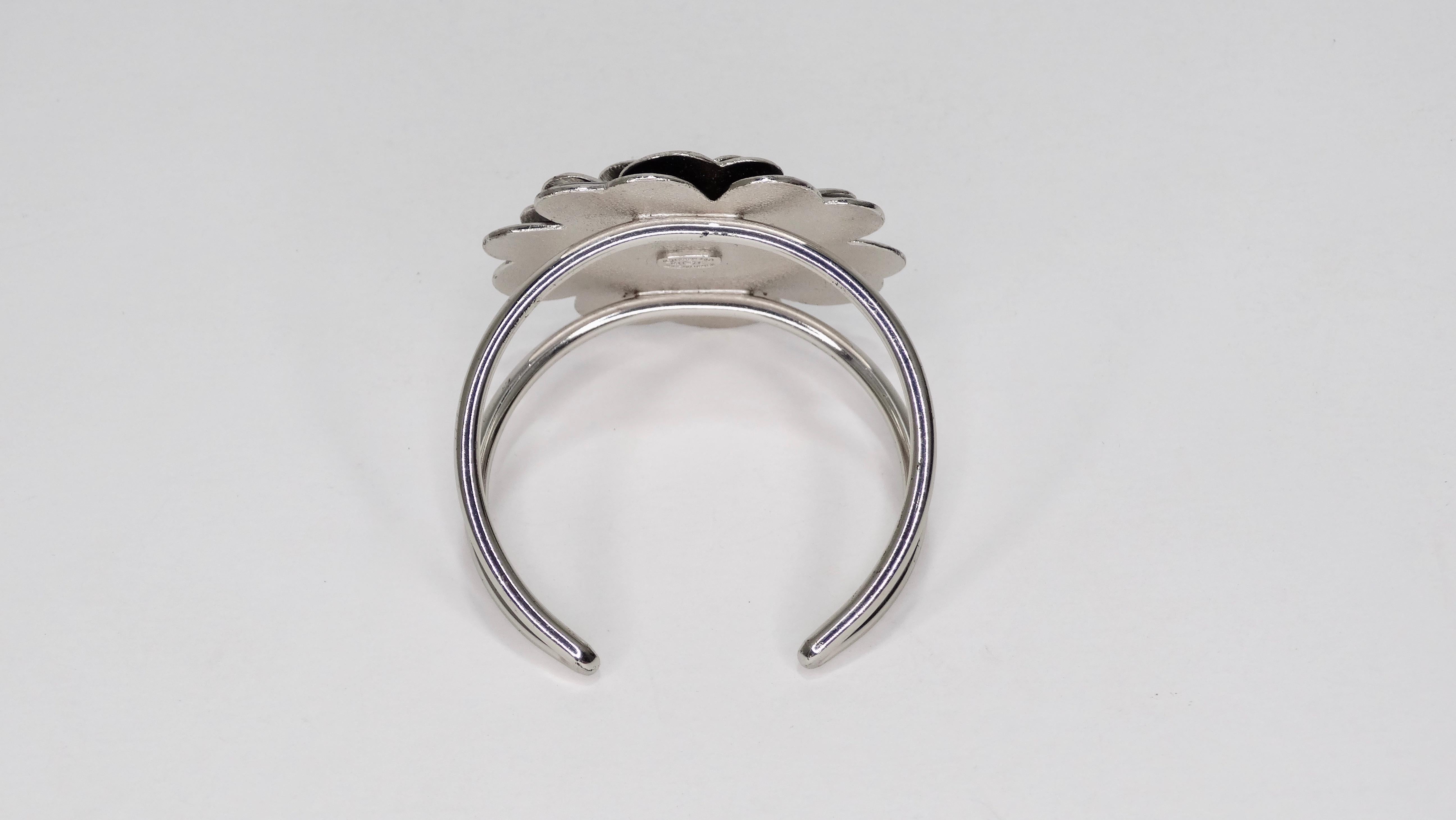 Can you say 'Classic?' Circa 2003 from Chanel's cruise collection, this silver Chanel cuff features a black enamel Camellia flower with a CC in the center. This cuff features an open backing for easy wear. This piece is extremely versatile and can