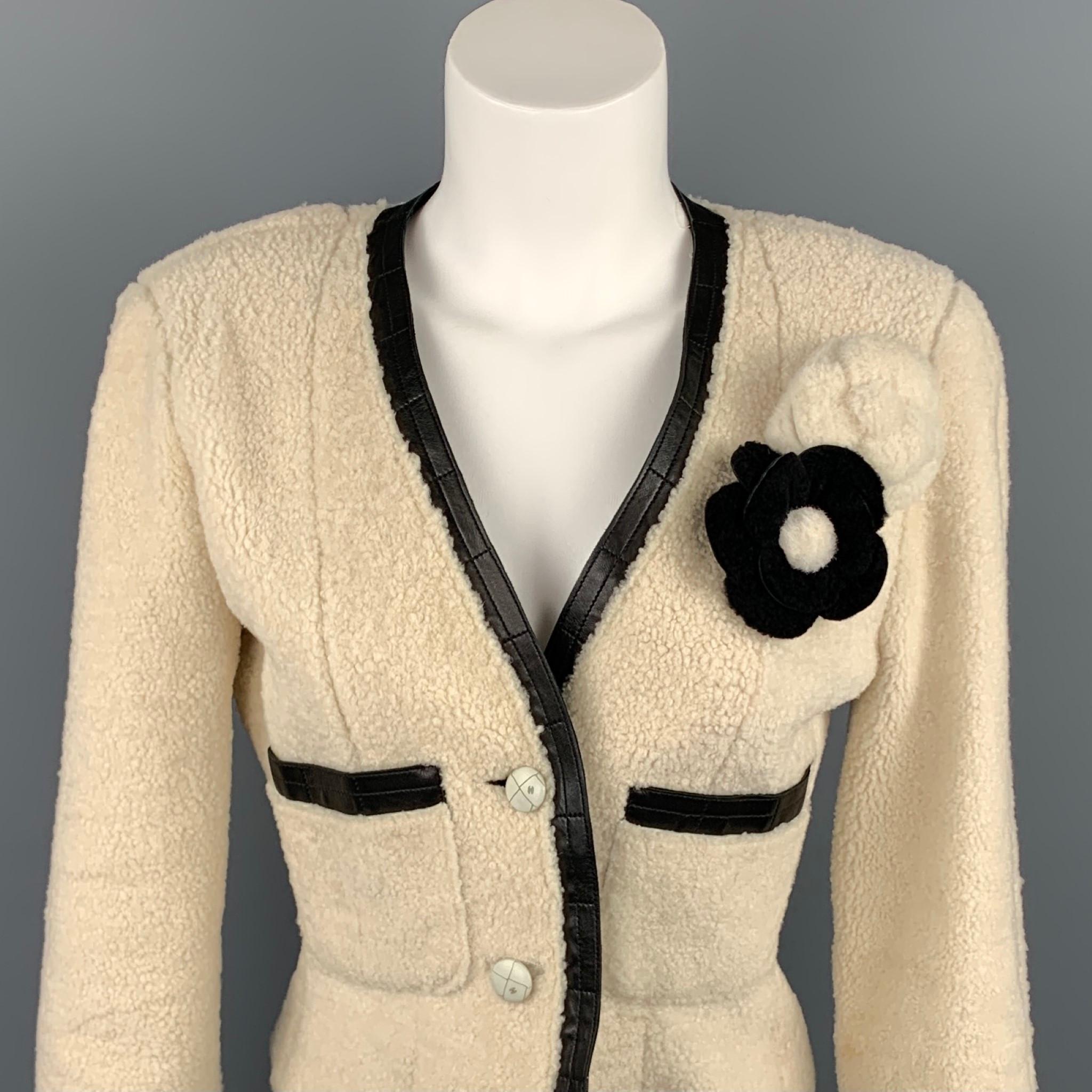 CHANEL 2003 jacket comes in a cream shearling with a black leather trim featuring two camelia pins, front pockets, and a two button closure. Made in France.

Very Good Pre-Owned Condition.
Marked: FR 38

Measurements:

Shoulder: 16.5 in.
Bust: 34