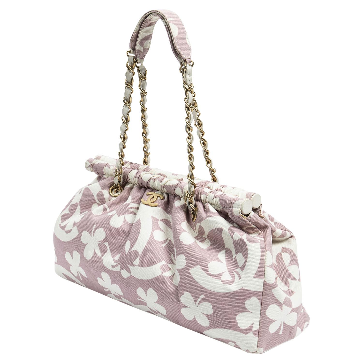 Dei primi anni 2000 (2004-2005), questa borsa è il perfetto portafortuna e la dimensione più perfetta per una borsa a tracolla. Realizzata in una vivace tela stampata rosa con logo Chanel sovradimensionato, quadrifoglio portafortuna e placca con