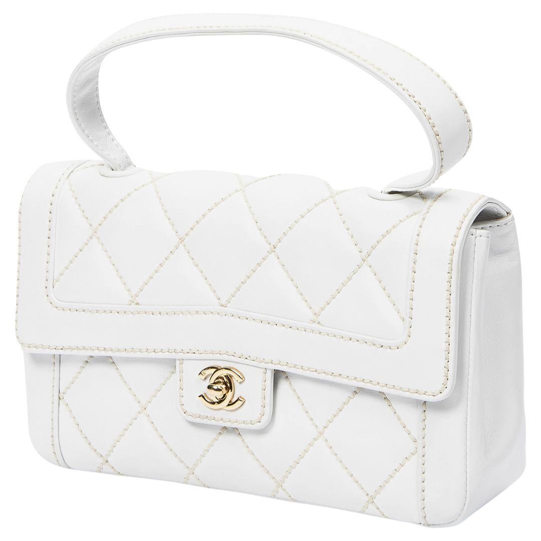 Embrace sophistication with the Chanel 2004 White Wild Stitch Top Handle Bag. Crafted from white calfskin leather, it showcases gold-tone hardware and a CC turnlock closure. The logo Jacquard-lined interior offers a zippered pocket and a slip pocket