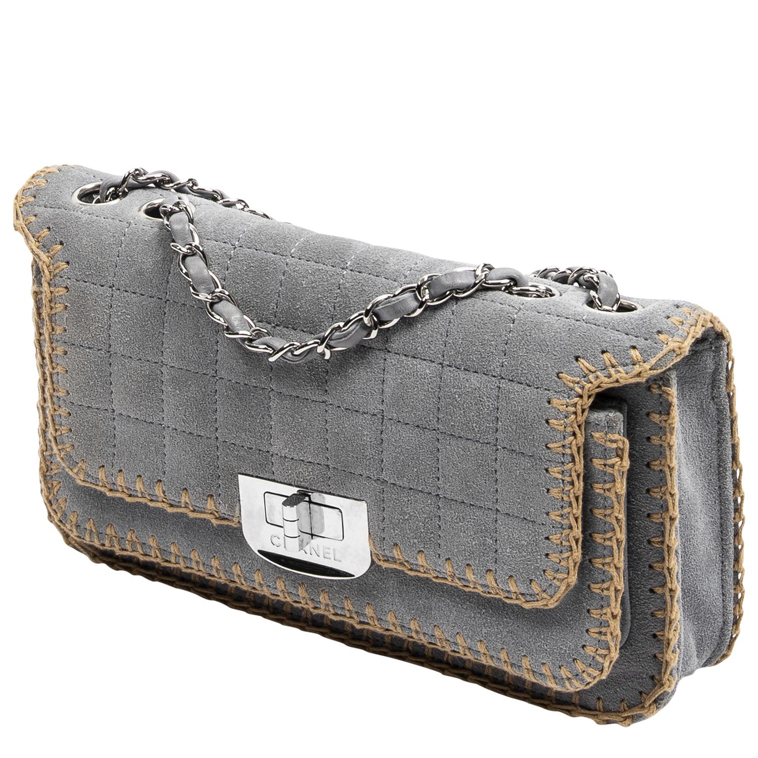 We can't believe our eyes! This rare vintage Chanel is detailed in light grey quilted suede with contrast stitching, silver-tone hardware, and dual interwoven chainlink shoulder straps. The Mademoiselle turnlock closure opens to a stunning grosgrain