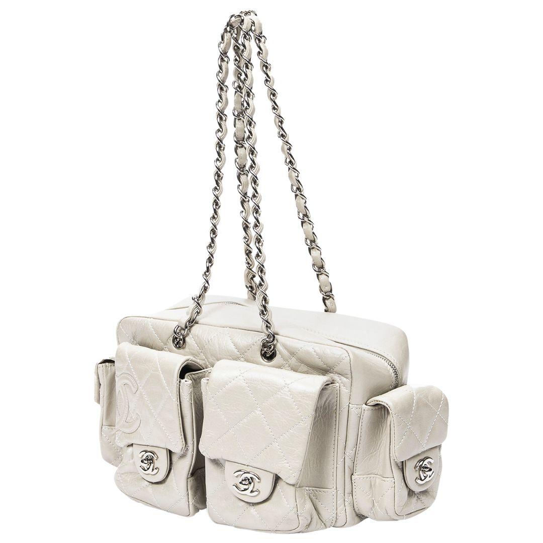 The Chanel 2006 Ivory Cambon Multi Pocket Bag is a fusion of style and functionality. Crafted from ivory calfskin leather, it features silver-tone hardware and a zipper closure. The grosgrain-lined interior boasts a zippered pocket and two slip