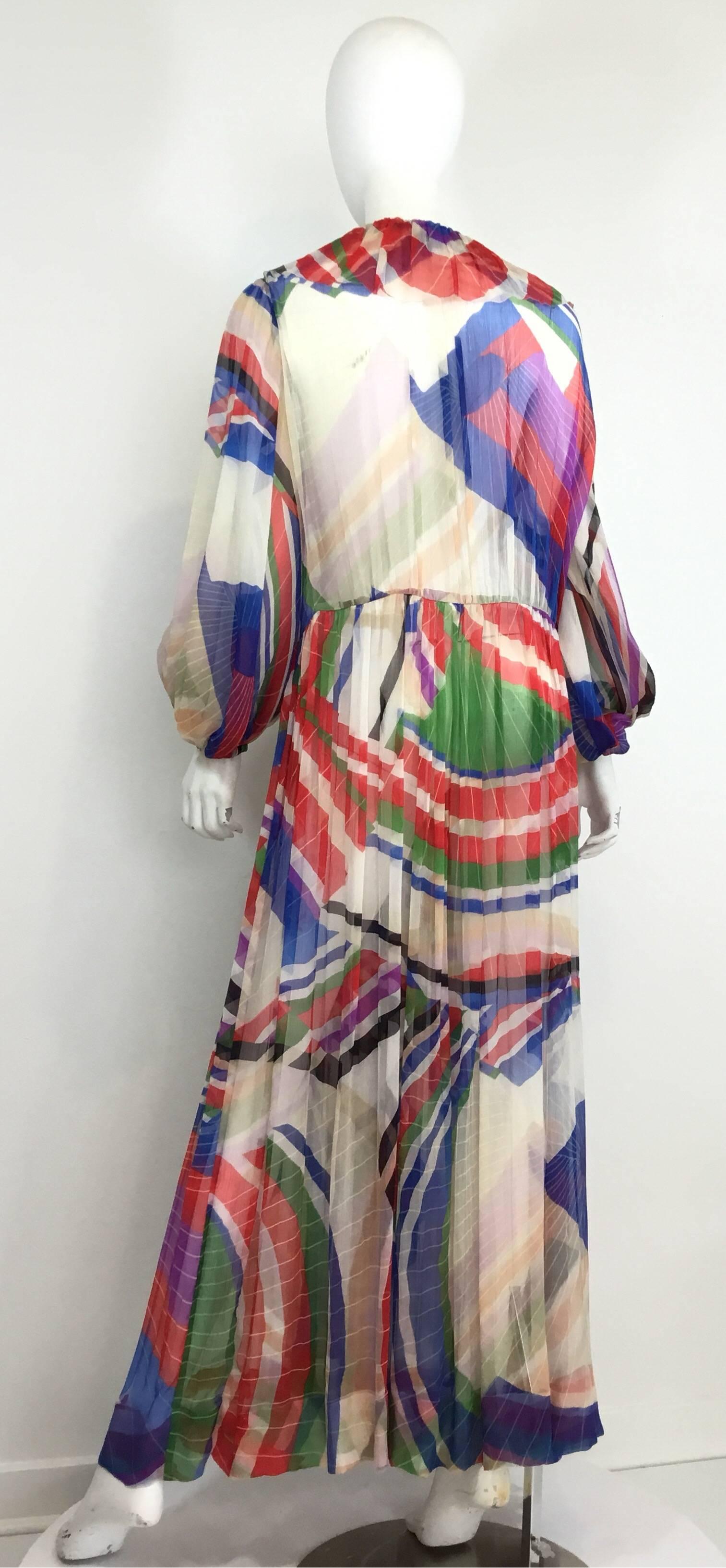 Chanel silk chiffon multicolored print gown or caftan features a concealed hook & eye and button closures at the front center, billow sleeves with elasticized cuffs. Gown is labeled a size 48, 100% silk, made in France. There are a few minor pulls